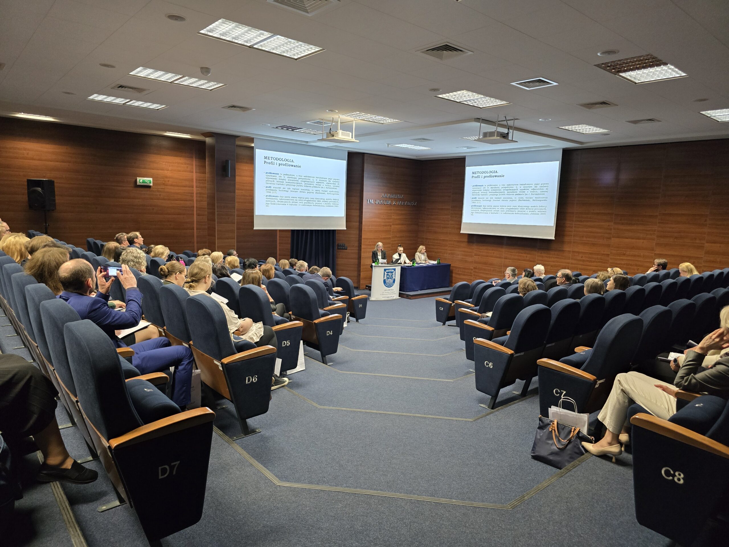 Na zdjęciu: prof. dr hab. Małgorzata Święcicka oraz dr Monika Peplińska. Przy stole prezydialnym siedzi prof. AJP dr hab. Agnieszka Niekrewicz.