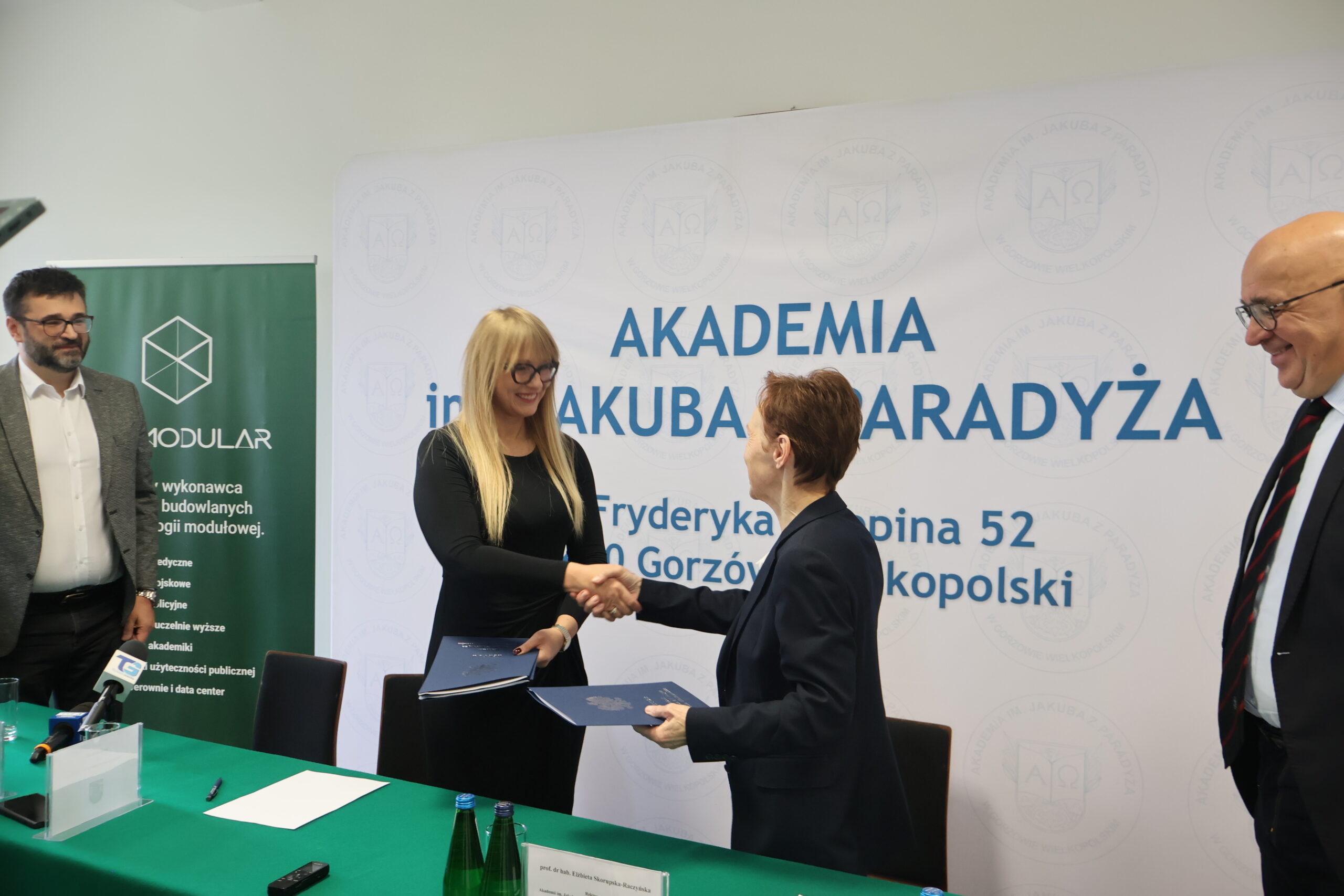Na zdjęciu od prawej za stołem: mgr Roman Gawroniak, Rektor Akademii im. Jakuba z Paradyża - prof. dr hab. Elżbieta Skorupska-Raczyńska, Prezes Zarządu Wykonawcy 3R MODULAR Pani Joanna podczas podpisania umowy - podanie sobie dłoni, uścisk