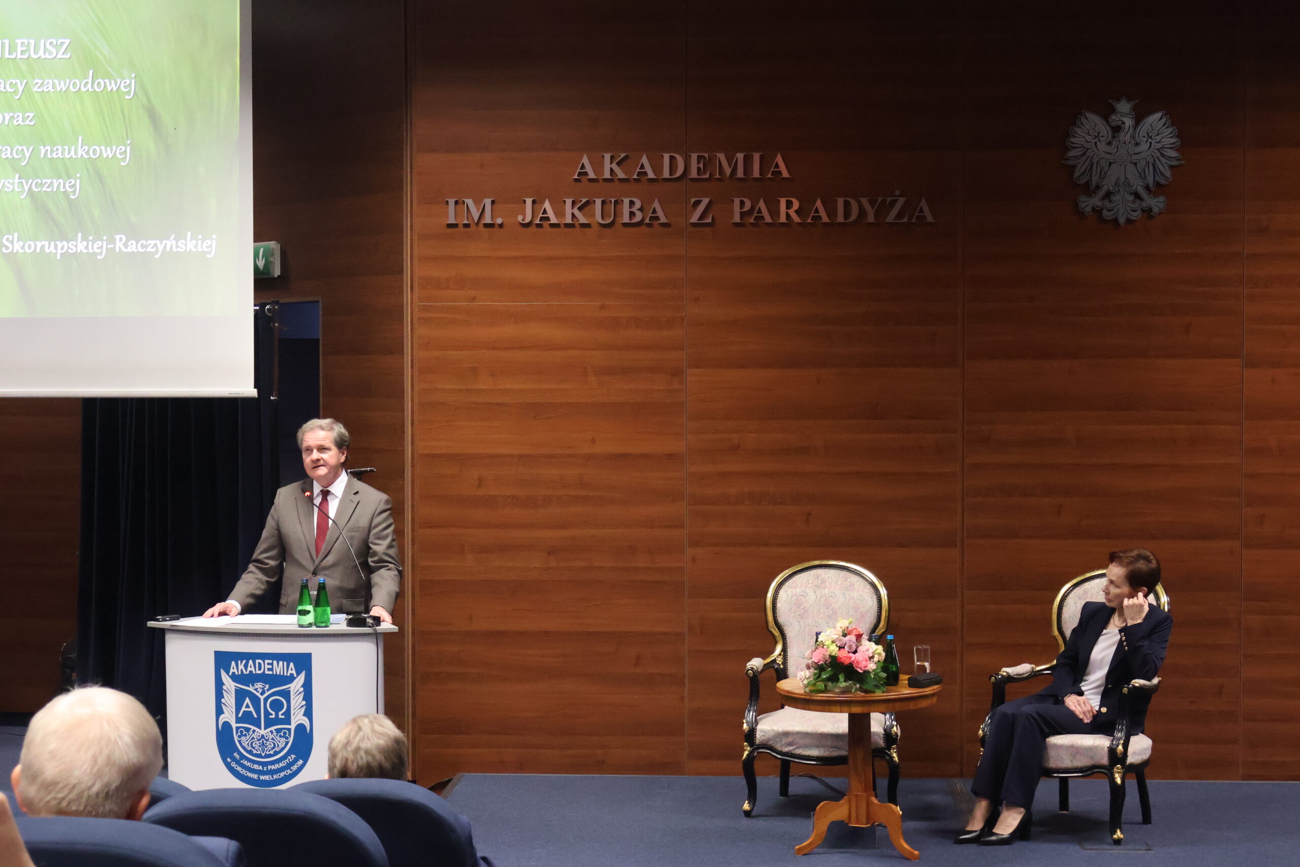 Na zdjęciu przemawia Prorektor ds. Nauki prof. dr hab. Grzegorz Kucharczyk oraz na fotelu siedzi Rektor Uczelni prof. dr hab. Elżbieta Skorupska-Raczyńska.