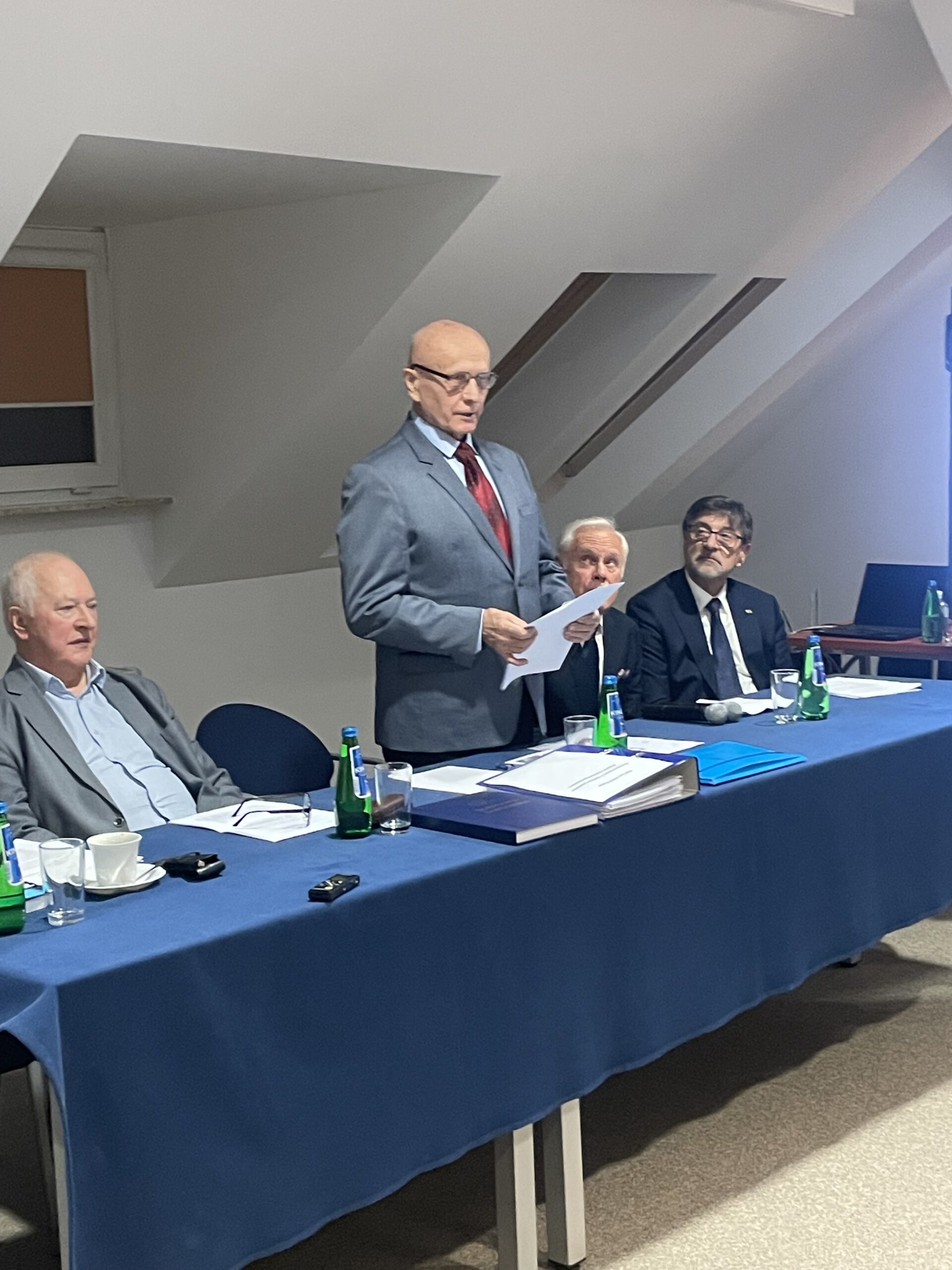 Promotor przemawia zza stołu komisyjnego.