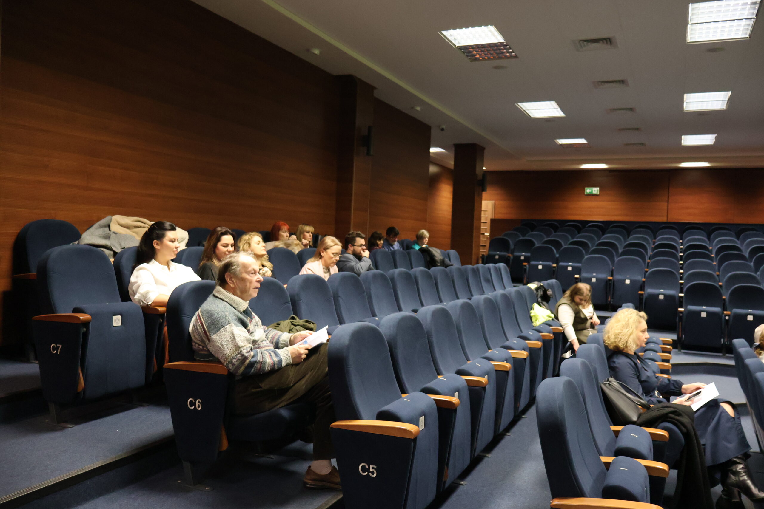 Grupa osób siedzi na Auli podczas konferencji.