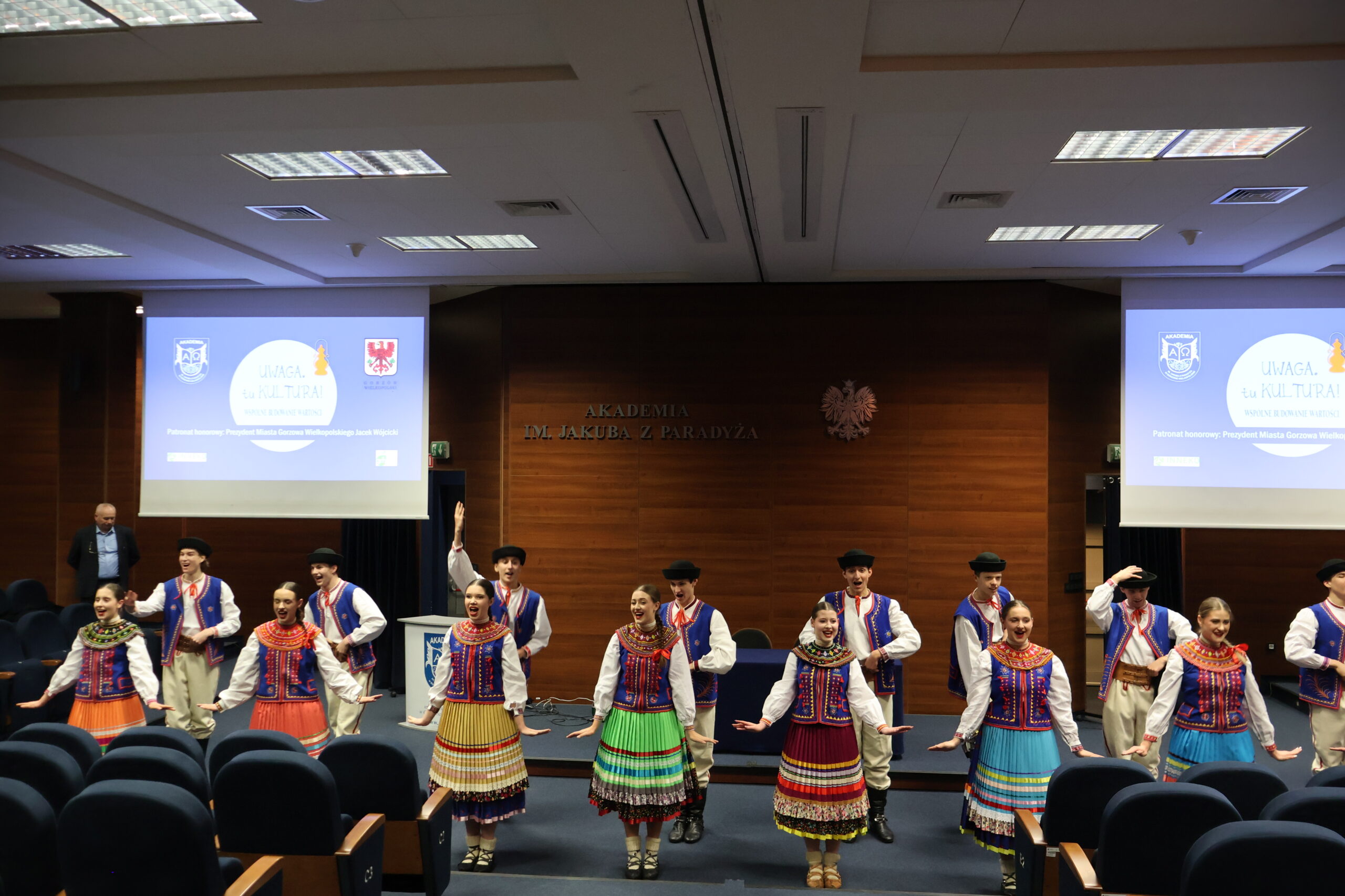 Zdjęcie całej grupy Zespołu Mali Gorzowiacy, którzy tańczą na Auli podczas konferencji.