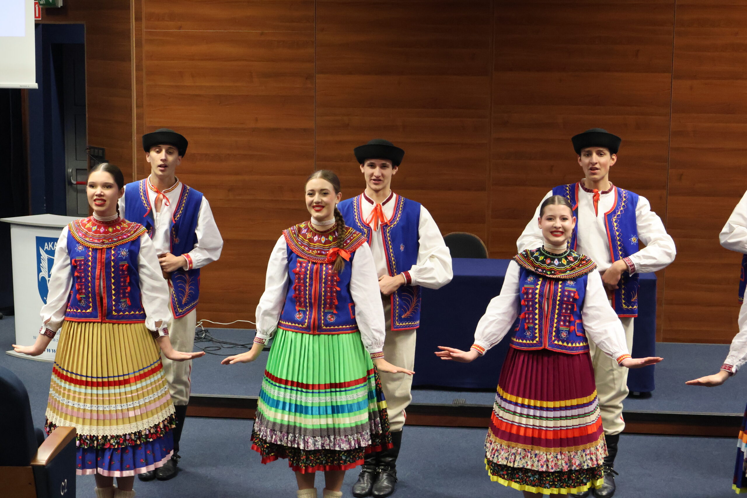 Grupa kobiet i mężczyzn z Zespołu Mali Gorzowiacy stoi na Auli podczas konferencji.