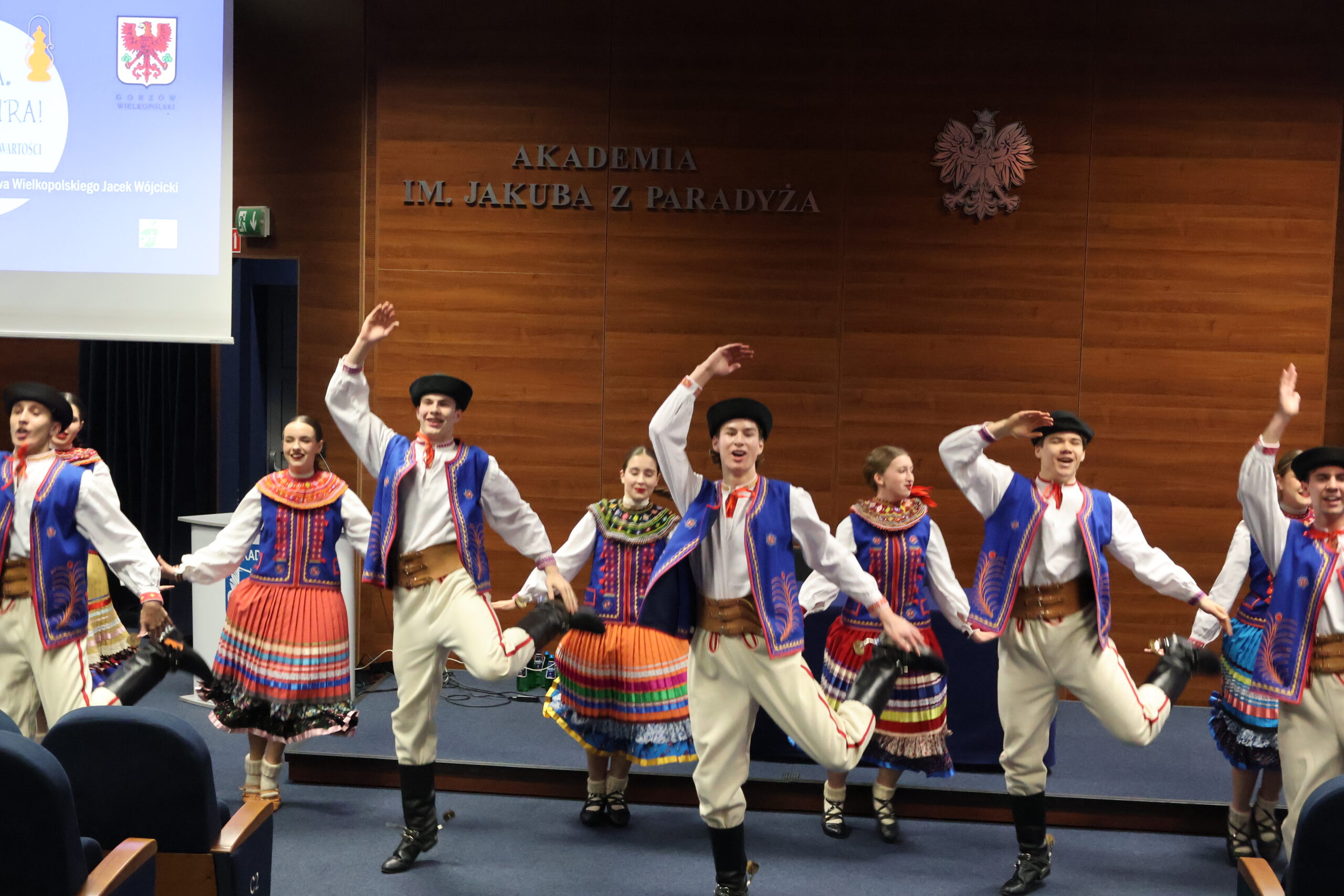 Grupa kobiet i mężczyzn z Zespołu Mali Gorzowiacy tańczy na Auli podczas konferencji.