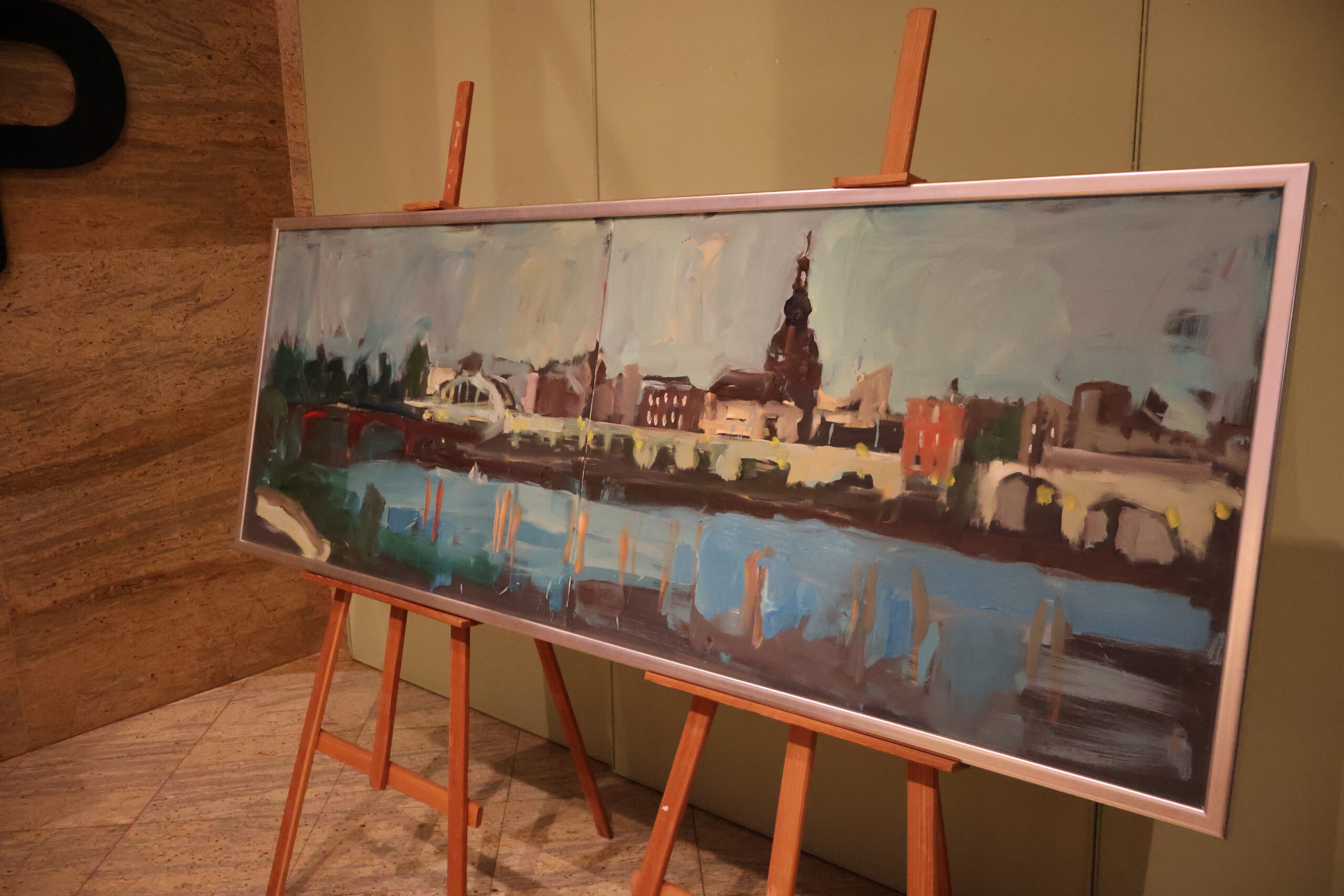 Duży obraz stojący na sztalugach, przedstawiający pejzaż miasta Gorzowa Wielkopolskiego.