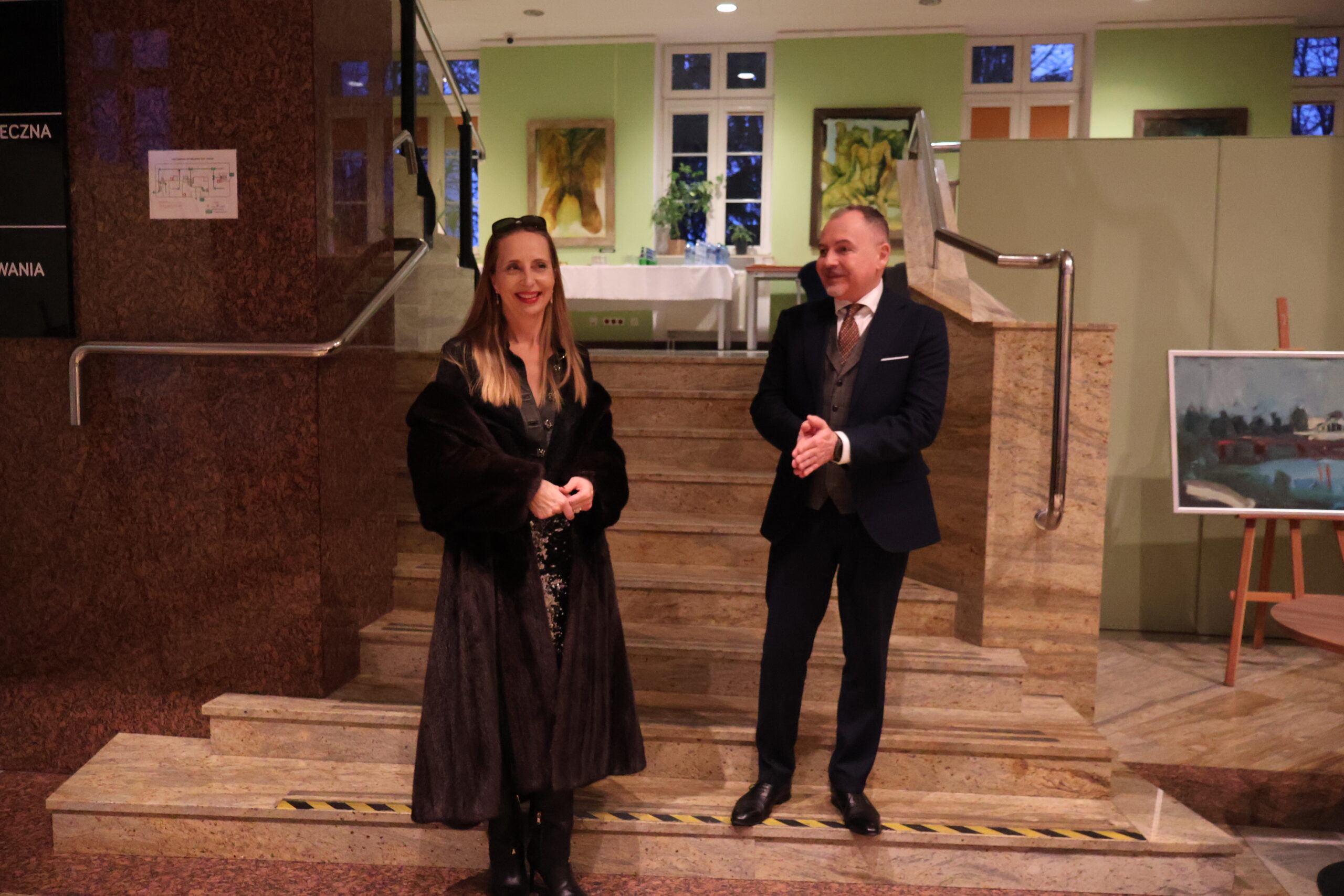 Na schodach stoi malarka z wykładowcą.