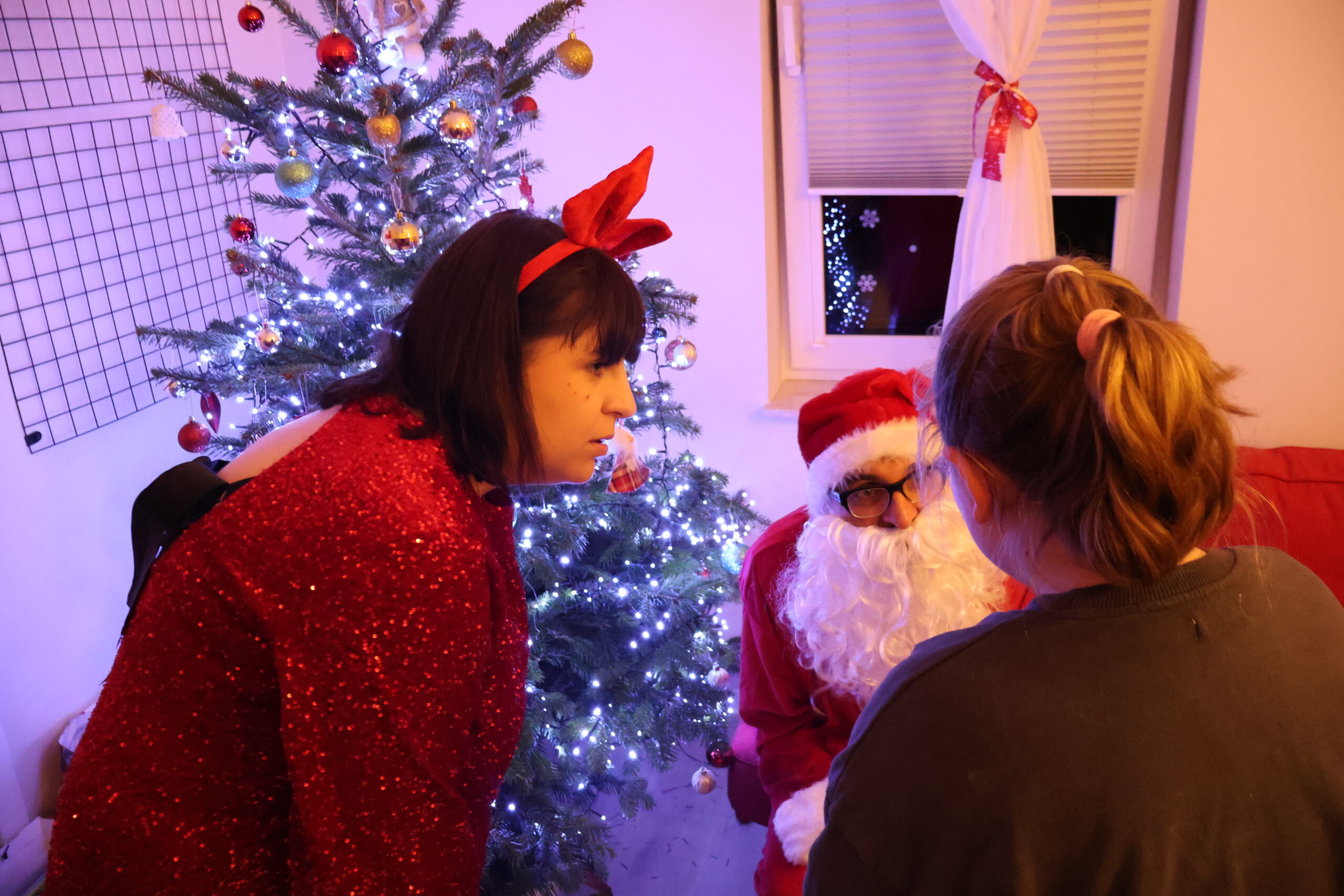 Mikołaj i jego Pomocnica, zwróceni twarzami do dziecka rozmawiają z nim