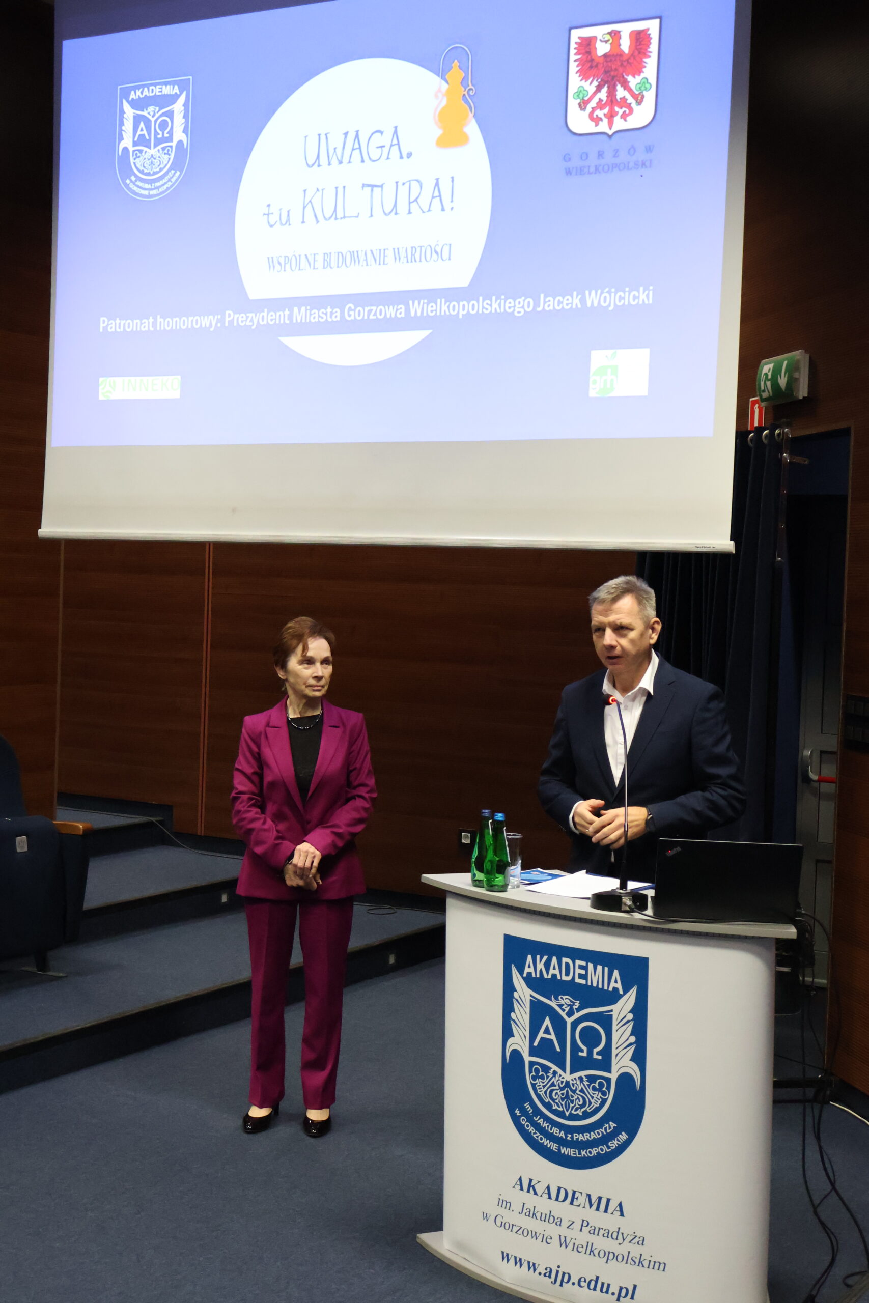 Po lewej stoi Pani Rektor, a po prawej za mównicą stoi mężczyzna.