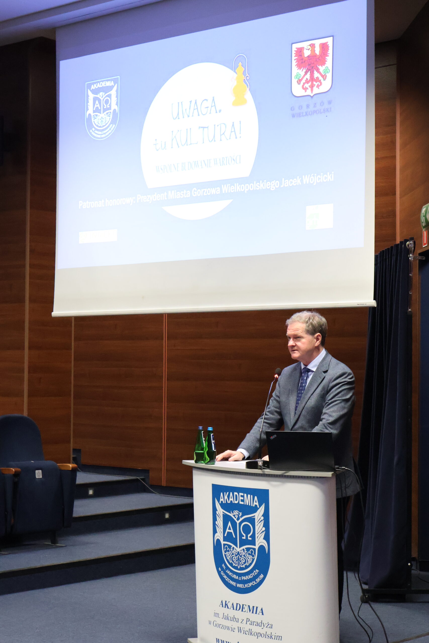 Pan Prorektor stoi za mównicą podczas konferencji.