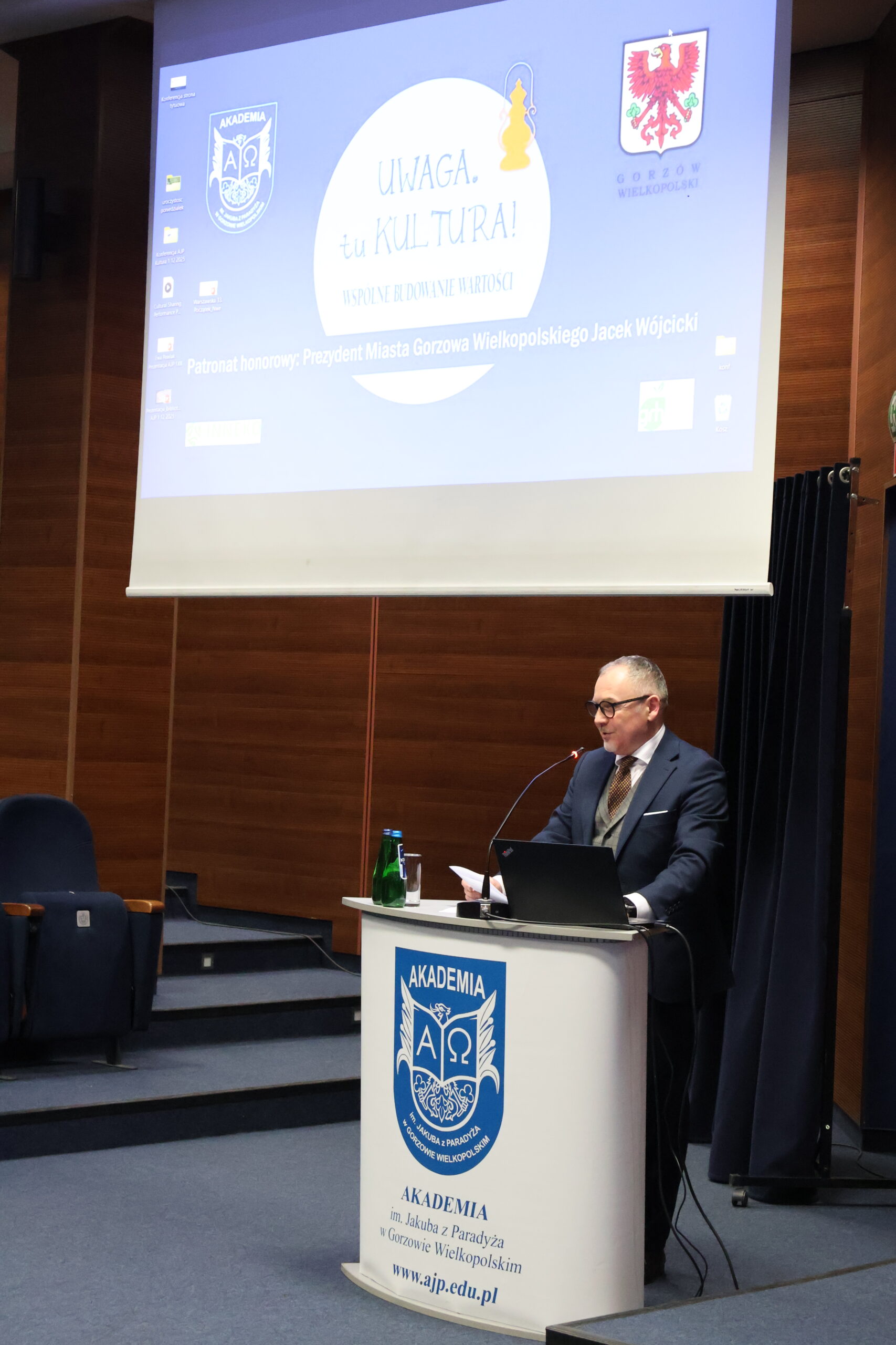 Wykładowca stoi za mównicą podczas konferencji.