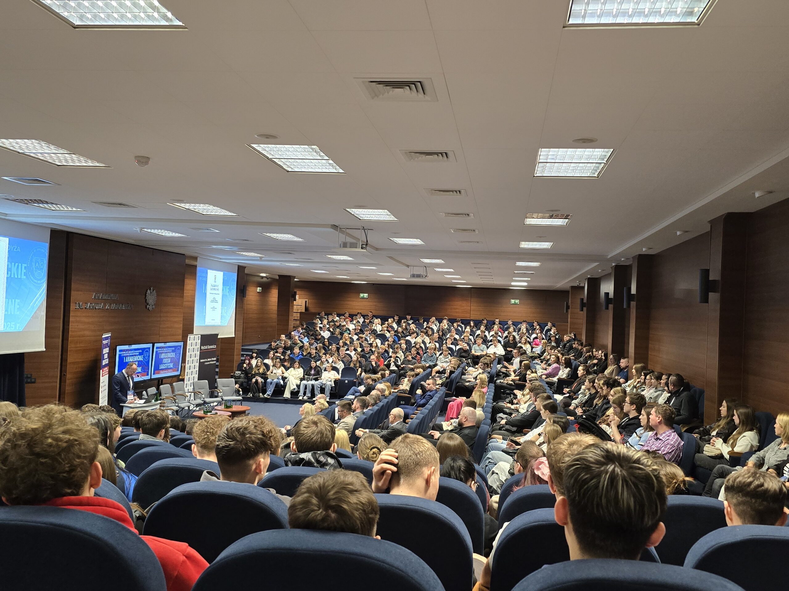 Grupa studentów siedzi w auli podczas konferencji.