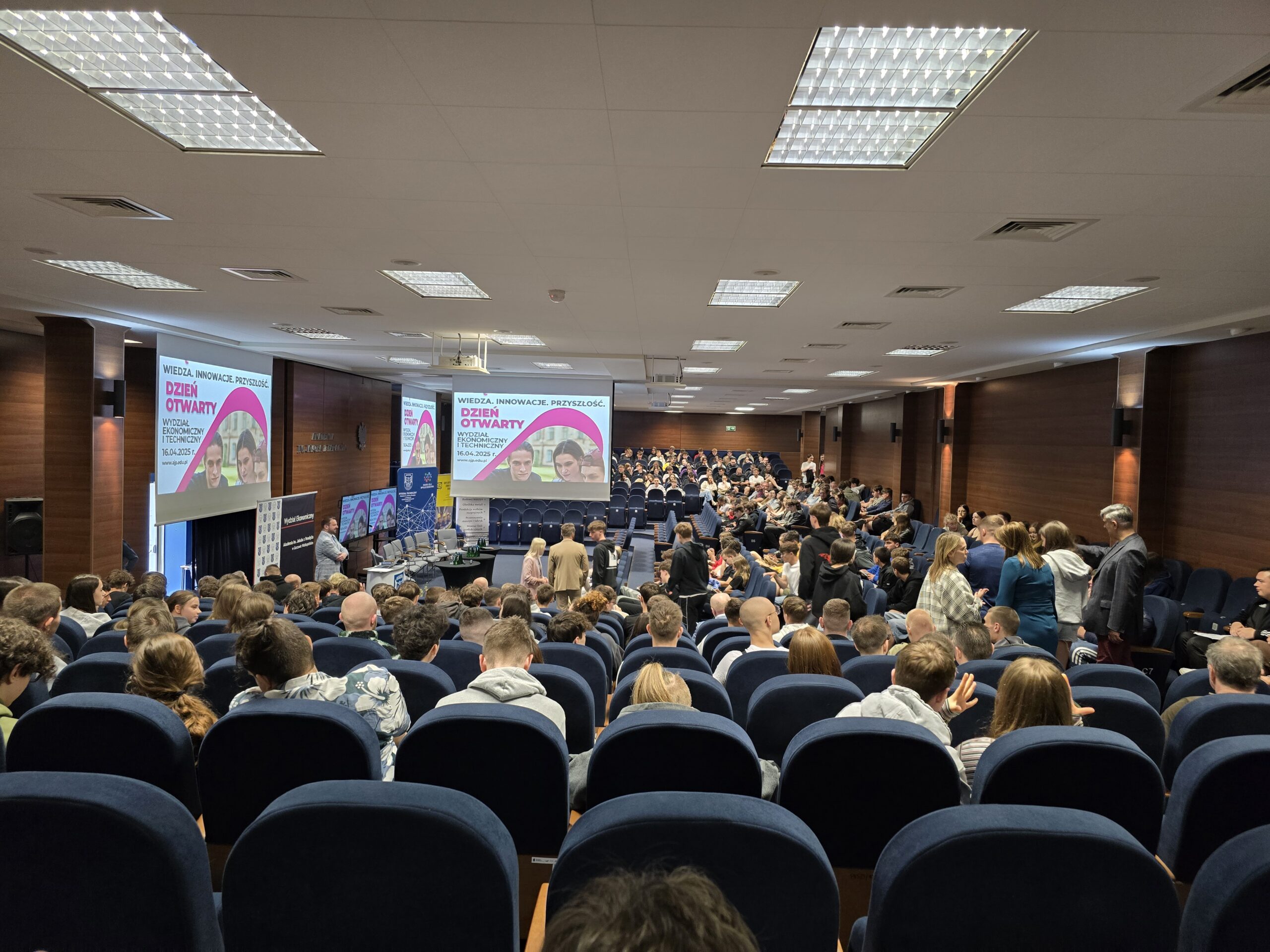 Grupa ludzi na auli podczas Dnia Otwartego AJP.