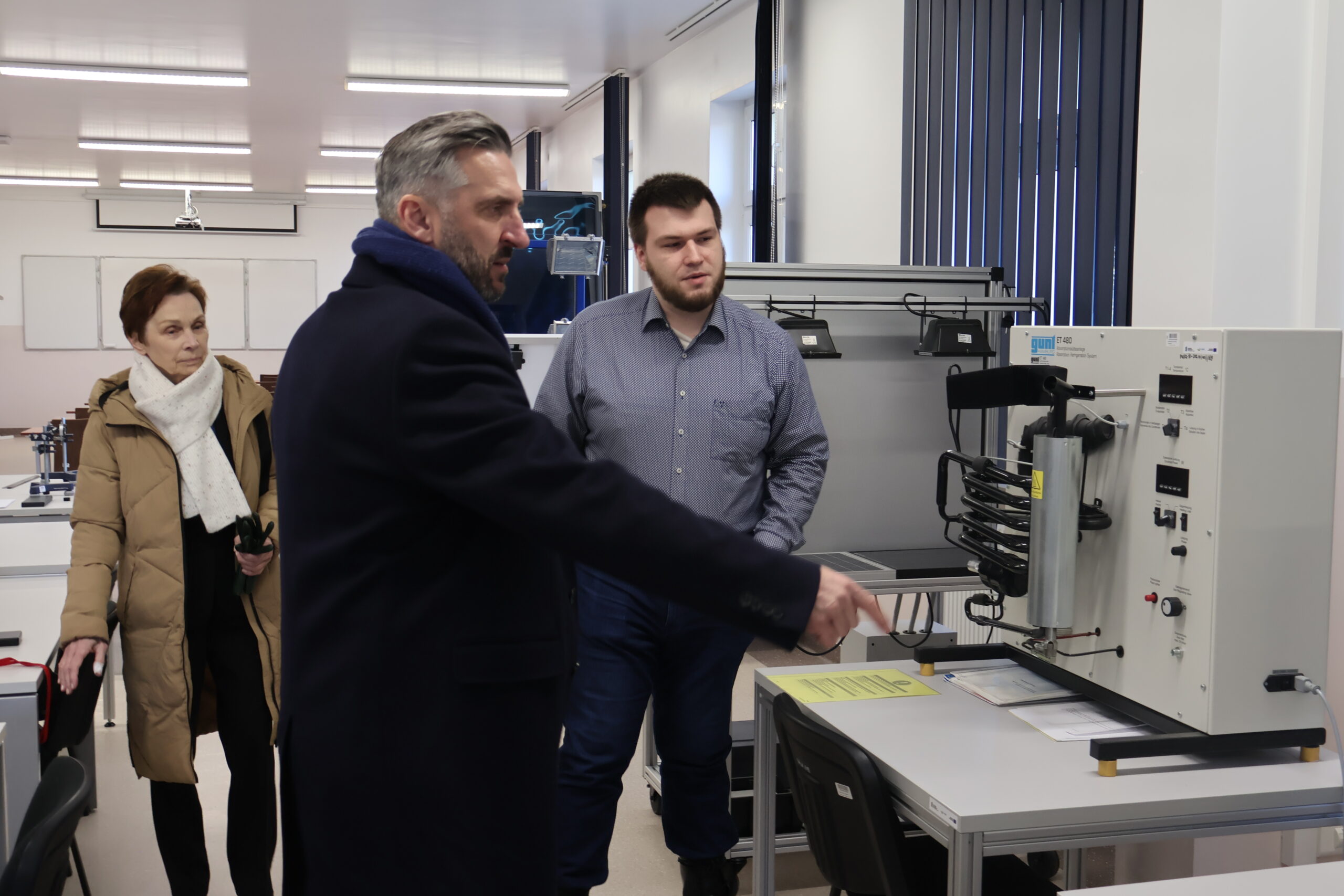Od lewej: JM Rektor prof. dr hab. Elżbieta Skorupska-Raczyńska Laborant Jan Kołaciński oraz poseł na Sejm RP prof. UZ dr hab. Waldemar Sługocki przy maszynie podczas wizyty w jednym laboratoriów w budynku nr 7.