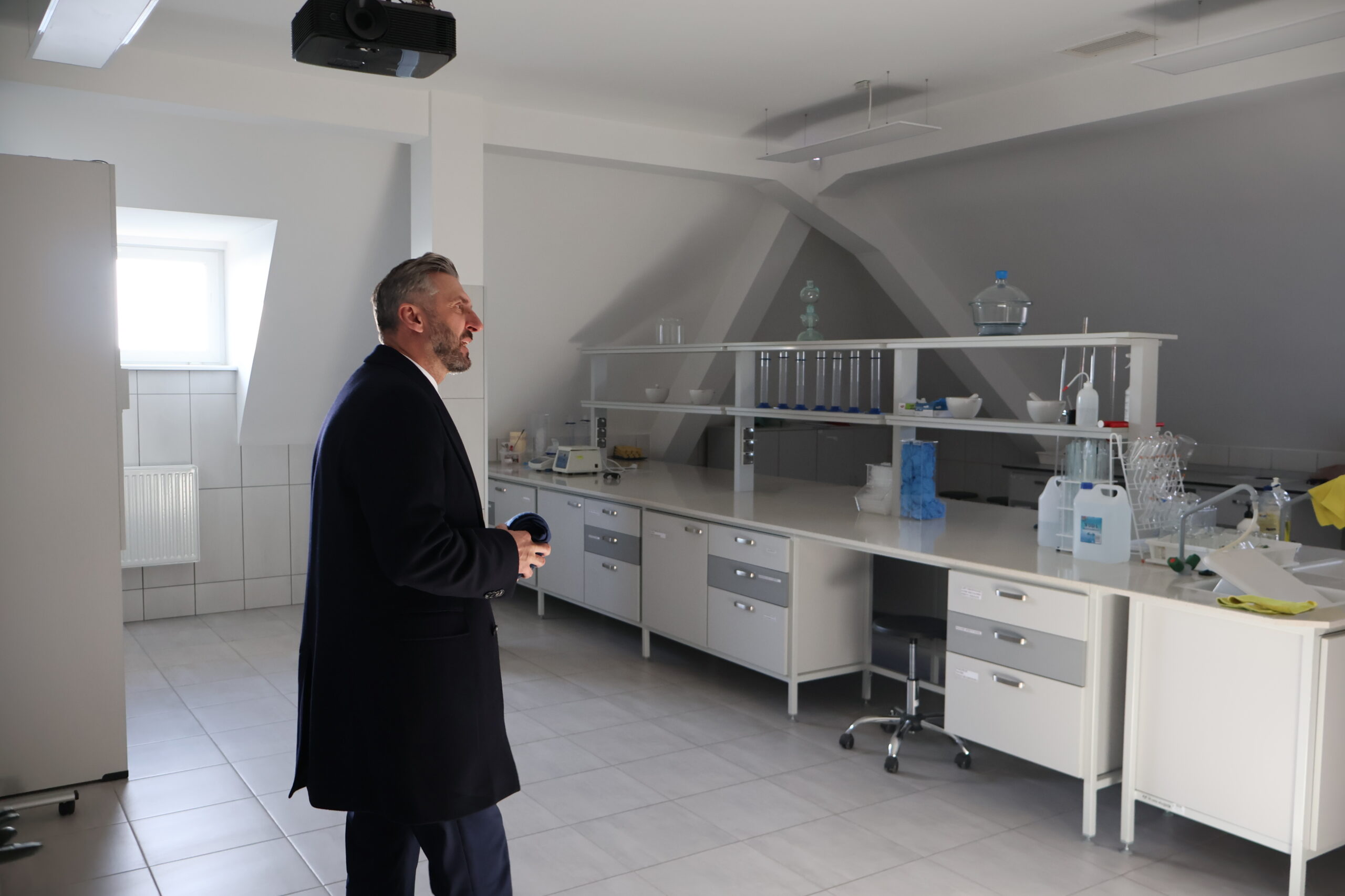 Poseł na Sejm RP prof. UZ dr hab. Waldemar Sługocki w gabinecie laboratorium chemicznego podziwiający wyposażenie.
