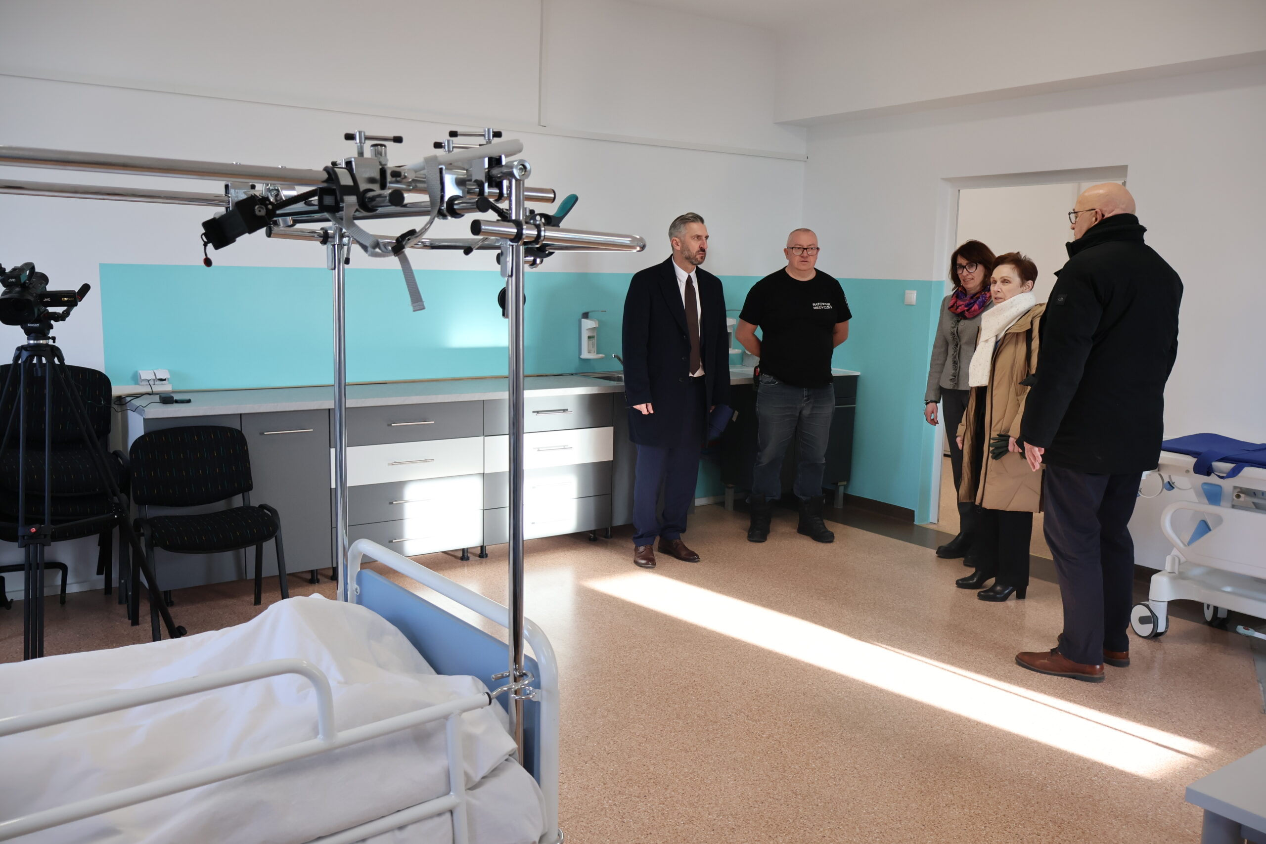 Od prawej: poseł na Sejm RP prof. UZ dr hab. Waldemar Sługocki, mgr Robert Sołtys pracownik WNZ - ratownik medyczny dr Joanna Kuriańska-Wołoszyn Prodziekan Wydziału Nauk o Zdrowiu, JM Rektor prof. dr hab. Elżbieta Skorupska-Raczyńska, Kanclerz Uczelni mgr Roman Gawroniak w gabinecie pielęgniarstwa rozmawiający o wyposażeniu.