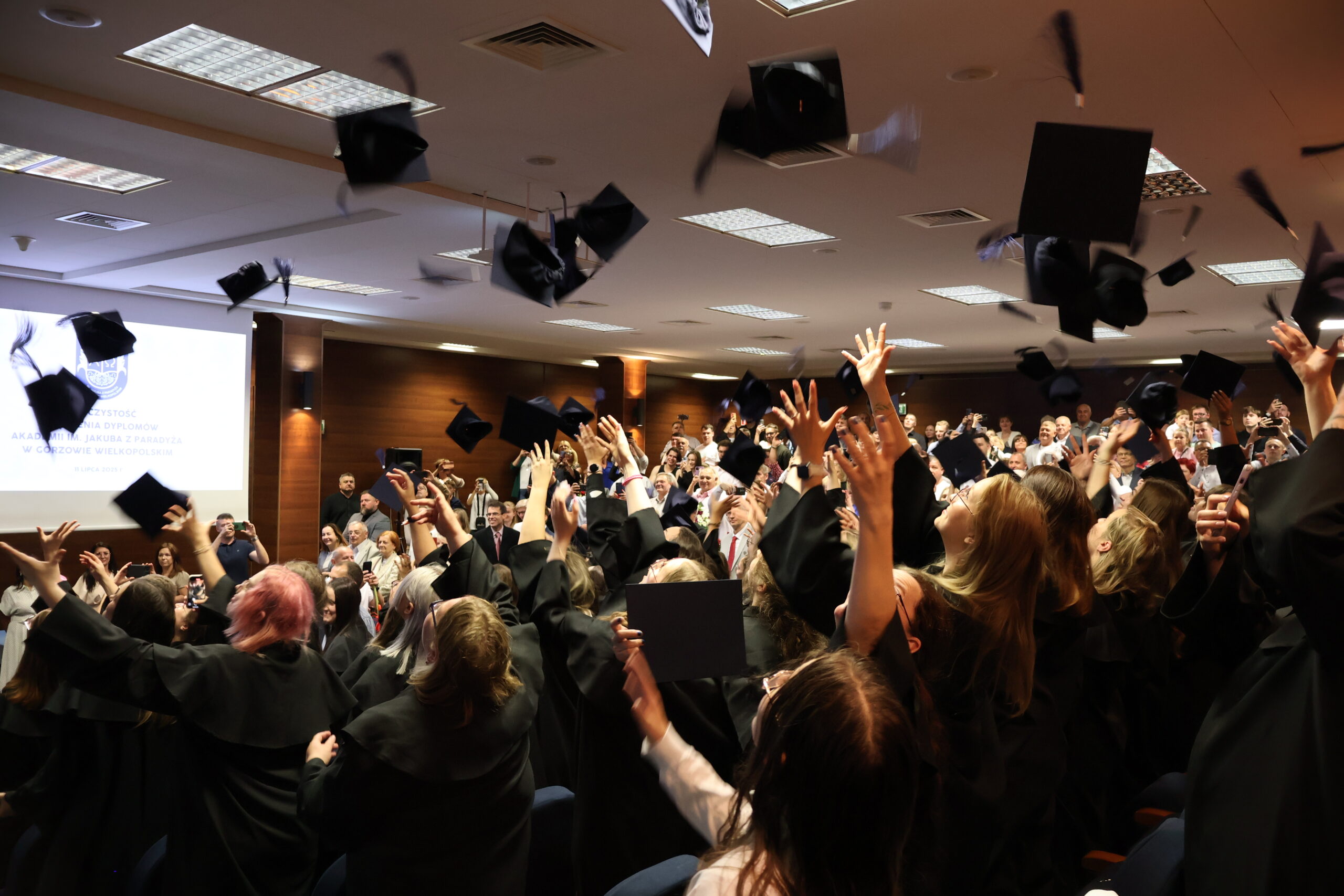 Absolwenci rzucają birety do góry podczas rozdania dyplomów.