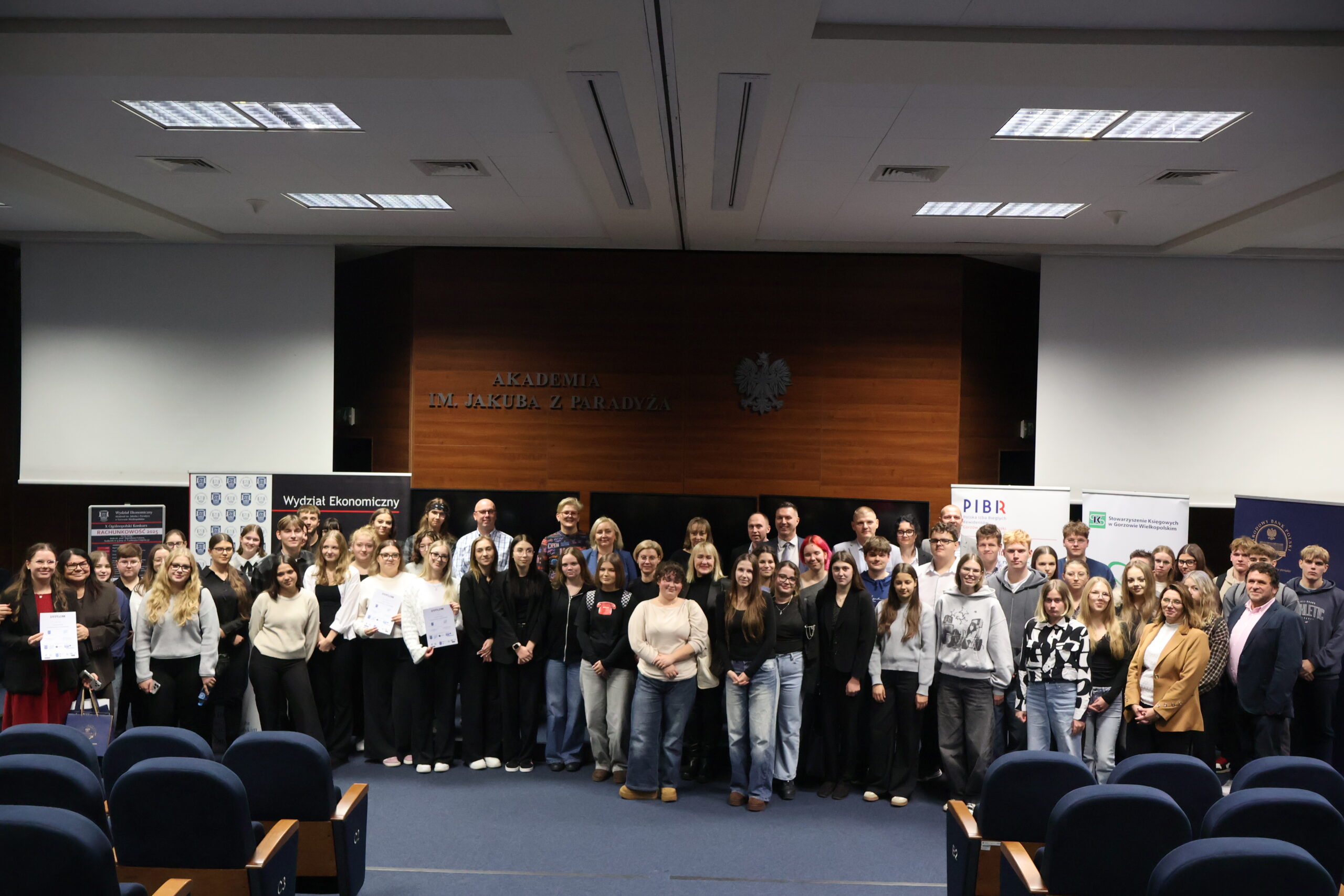 Grupa ludzi stoi przodem na auli.