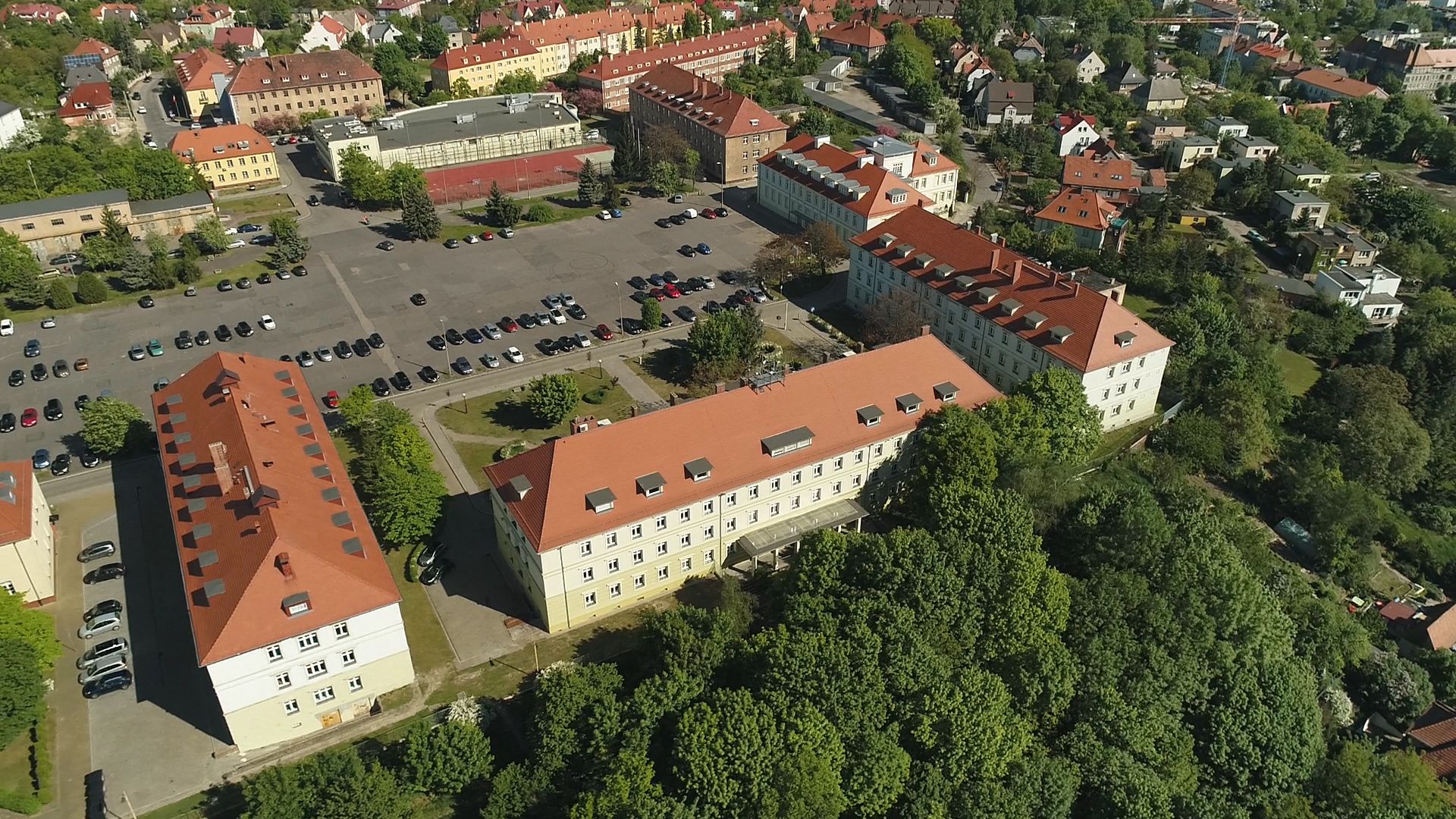 Widok z góry na kompleks budynków przy ul. Chopina 52, halę sportową i parking.