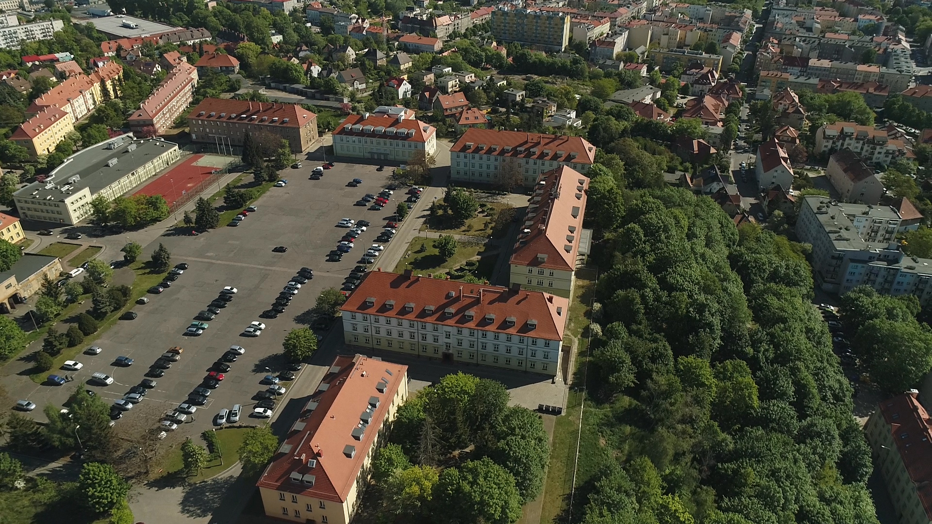 Widok z góry na kompleks budynków przy ul. Chopina 52, halę sportową i parking.