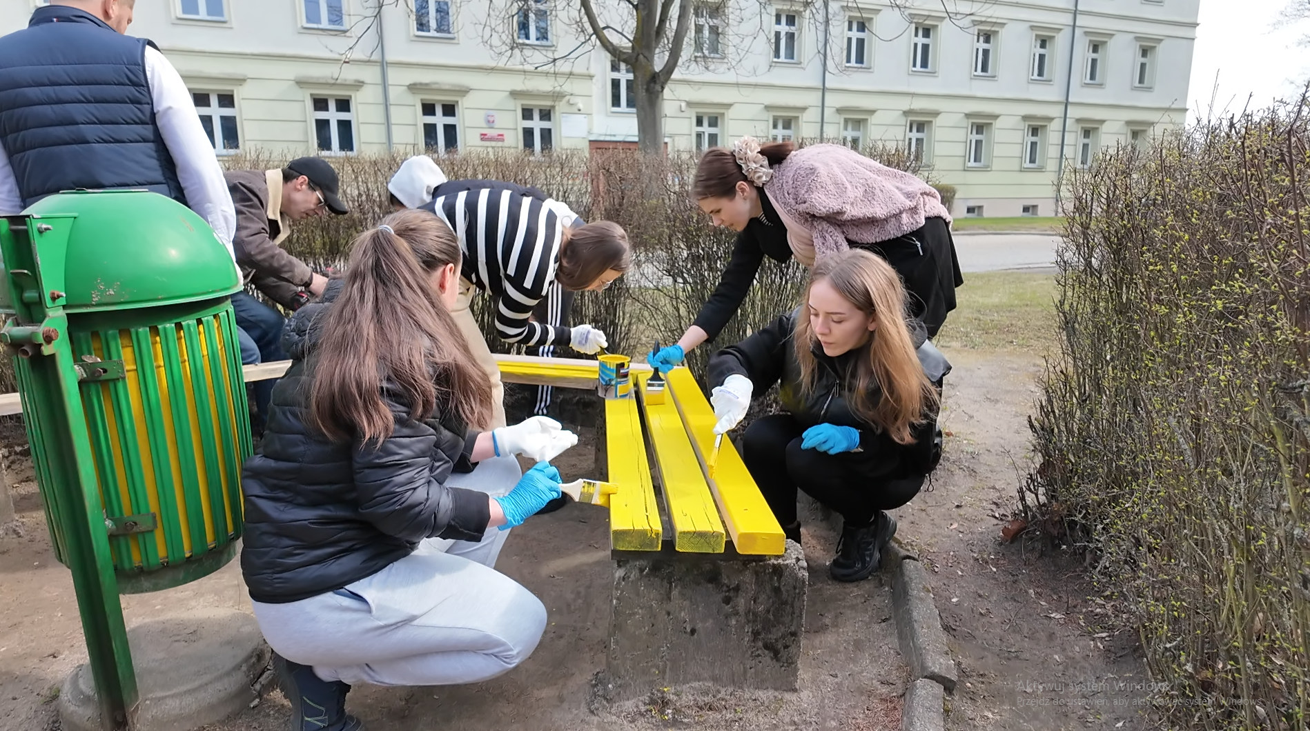 Grupa studentów maluje ławki.