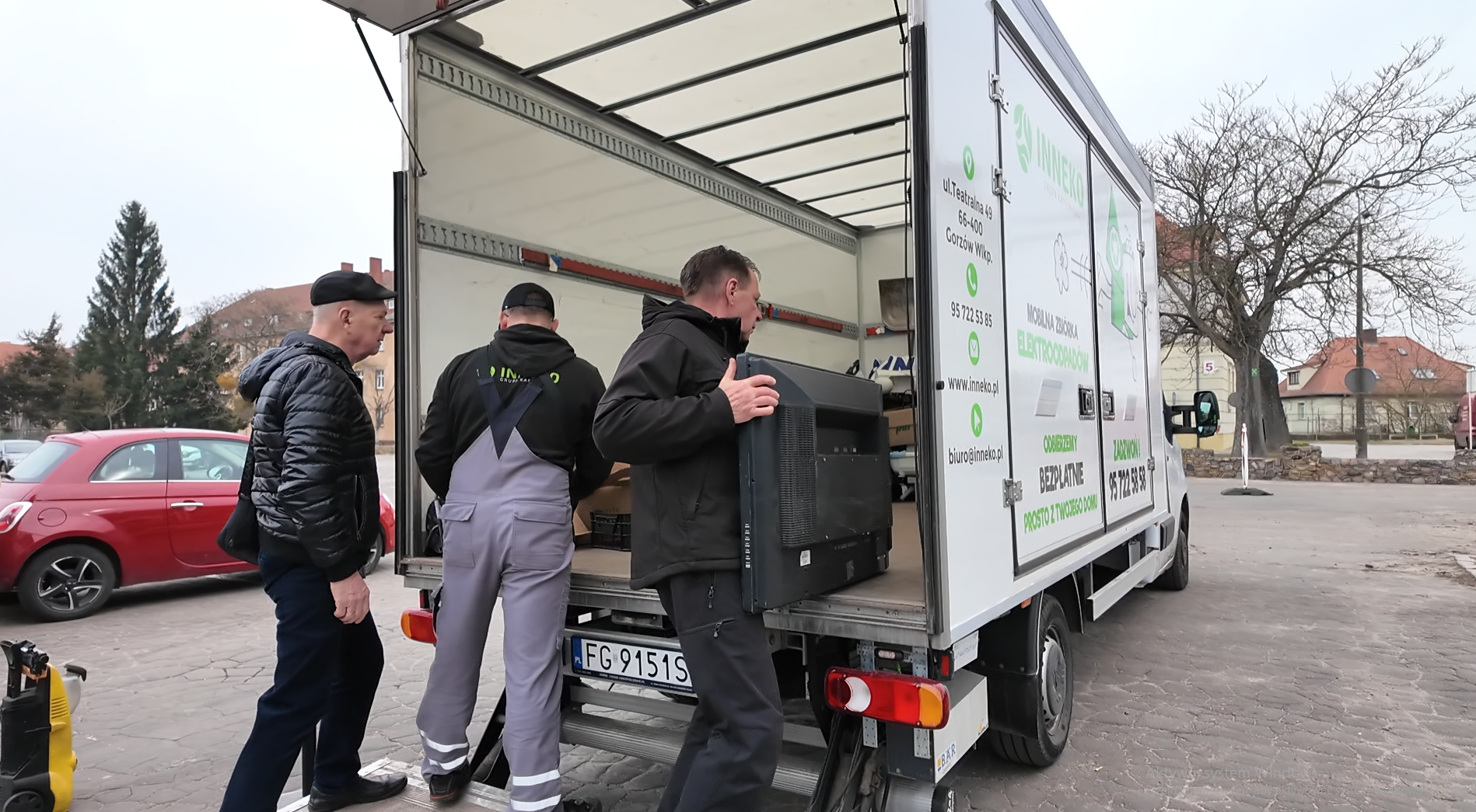 Trzy osoby stoją przy ciężarówce z elektrośmieciami.