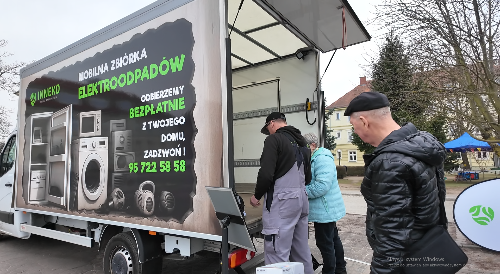 Trzy osoby stoją przy ciężarówce.