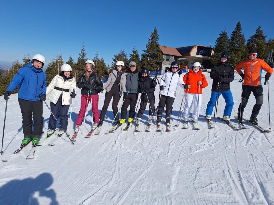 Dziesięciu uczestników zawodów stoi w rzędzie na stoku narciarskim.