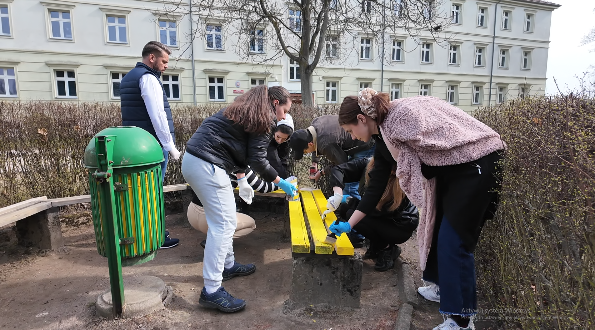 Grupa studentów i pracowników maluje ławki