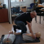 Ratownik medyczny pokazuje na fantomie zasady udzielania pierwszej pomocy.