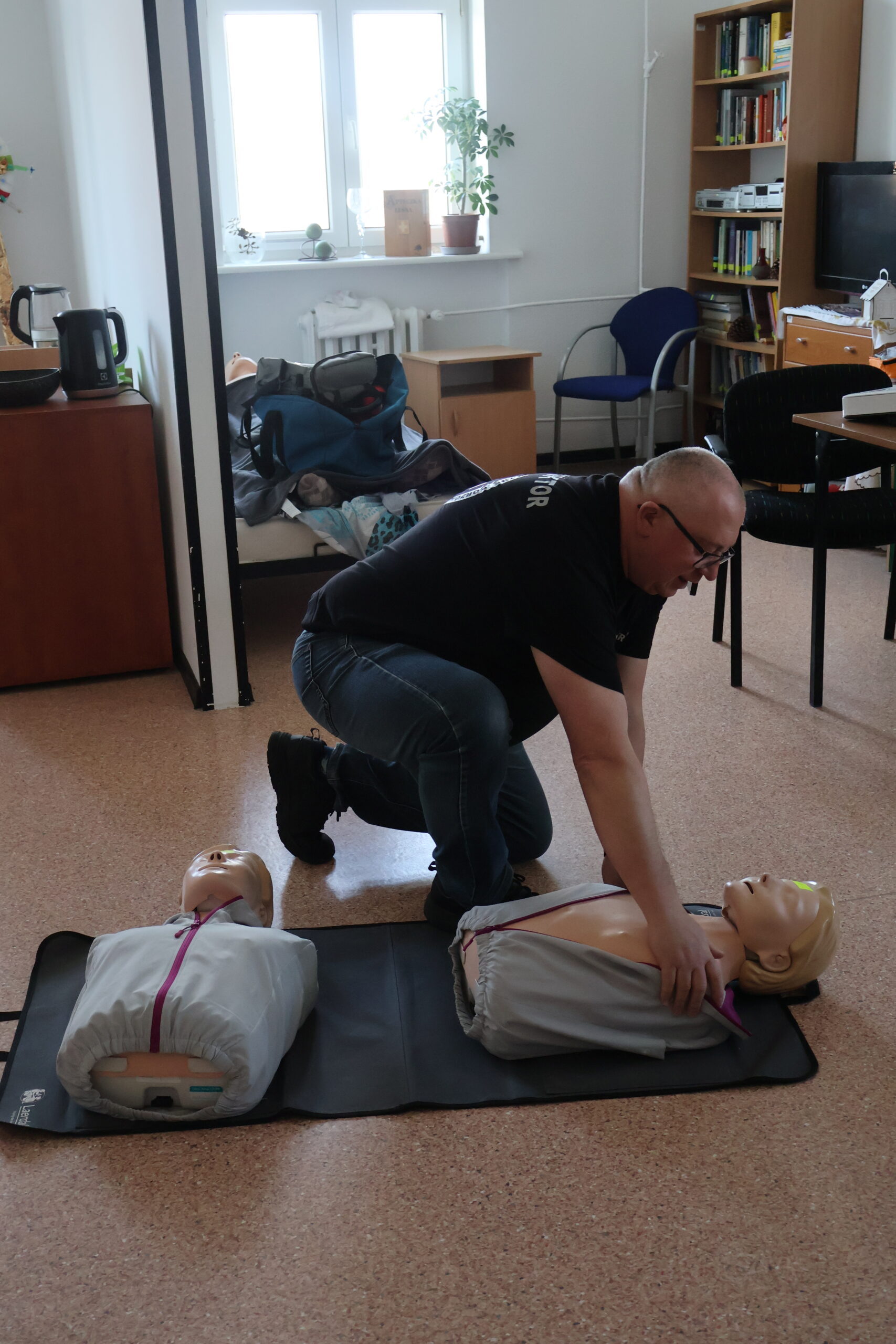 Ratownik medyczny pokazuje na fantomie zasady udzielania pierwszej pomocy.