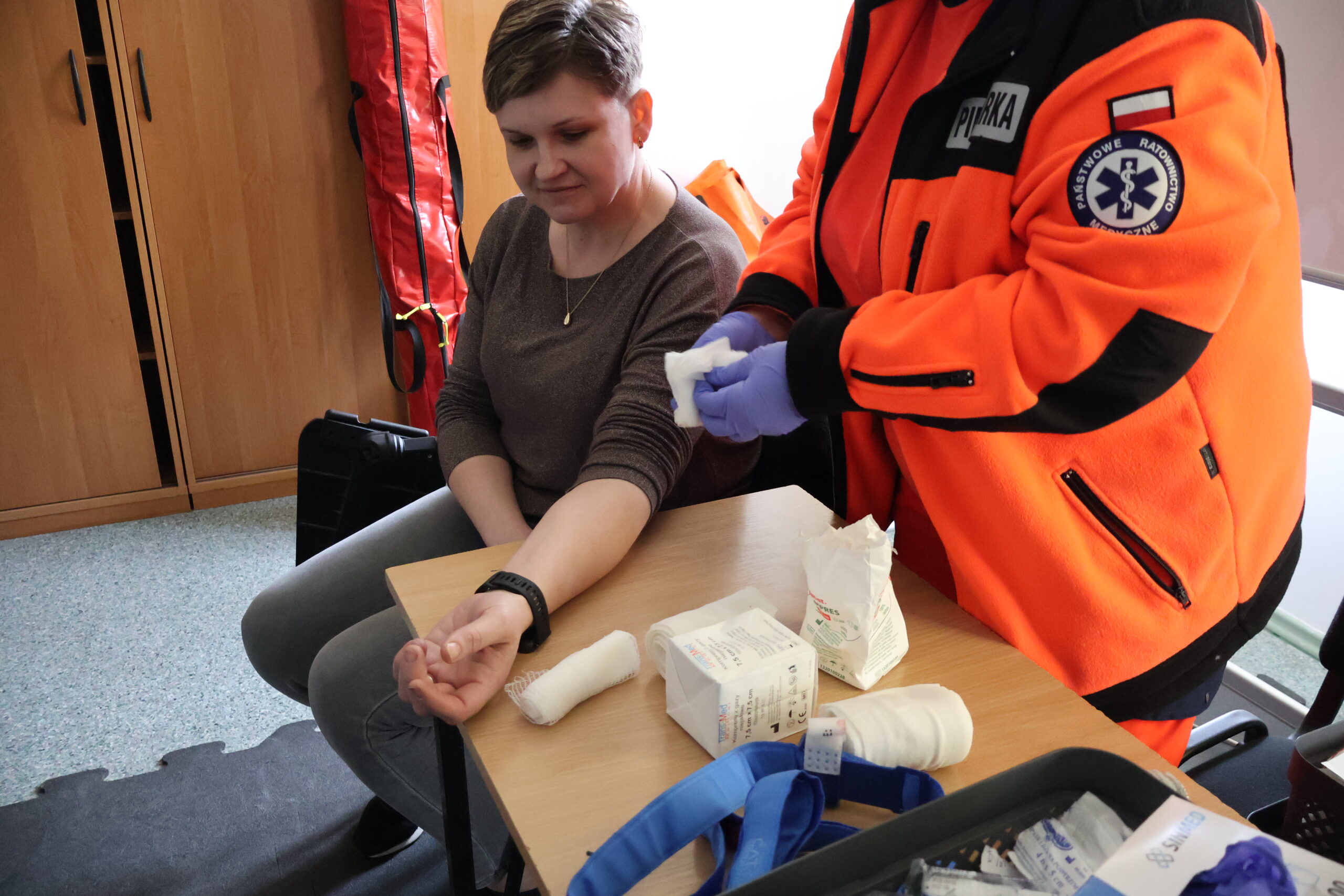 Ratownik medyczny zakłada opatrunek kobiecie.