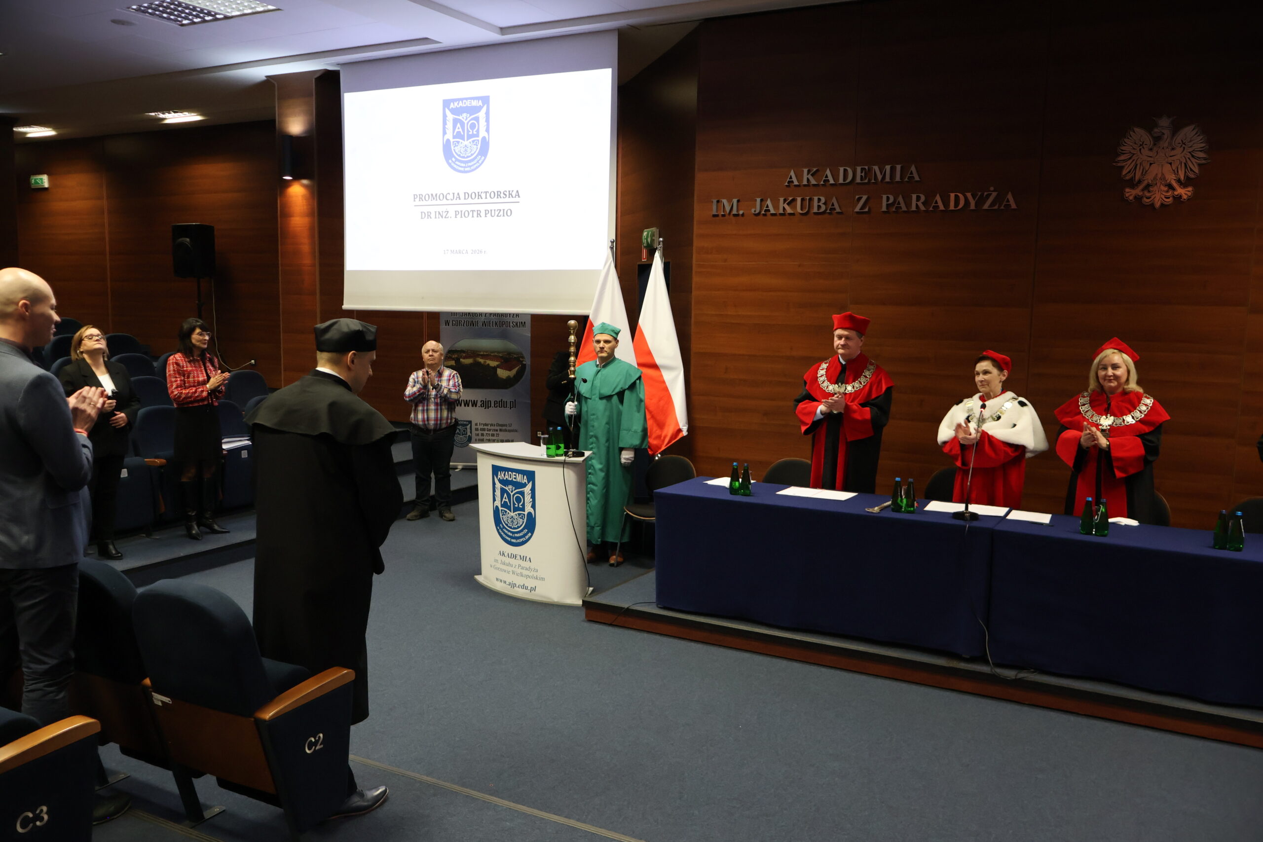 Uczestnicy uroczystości stoją i biją brawo