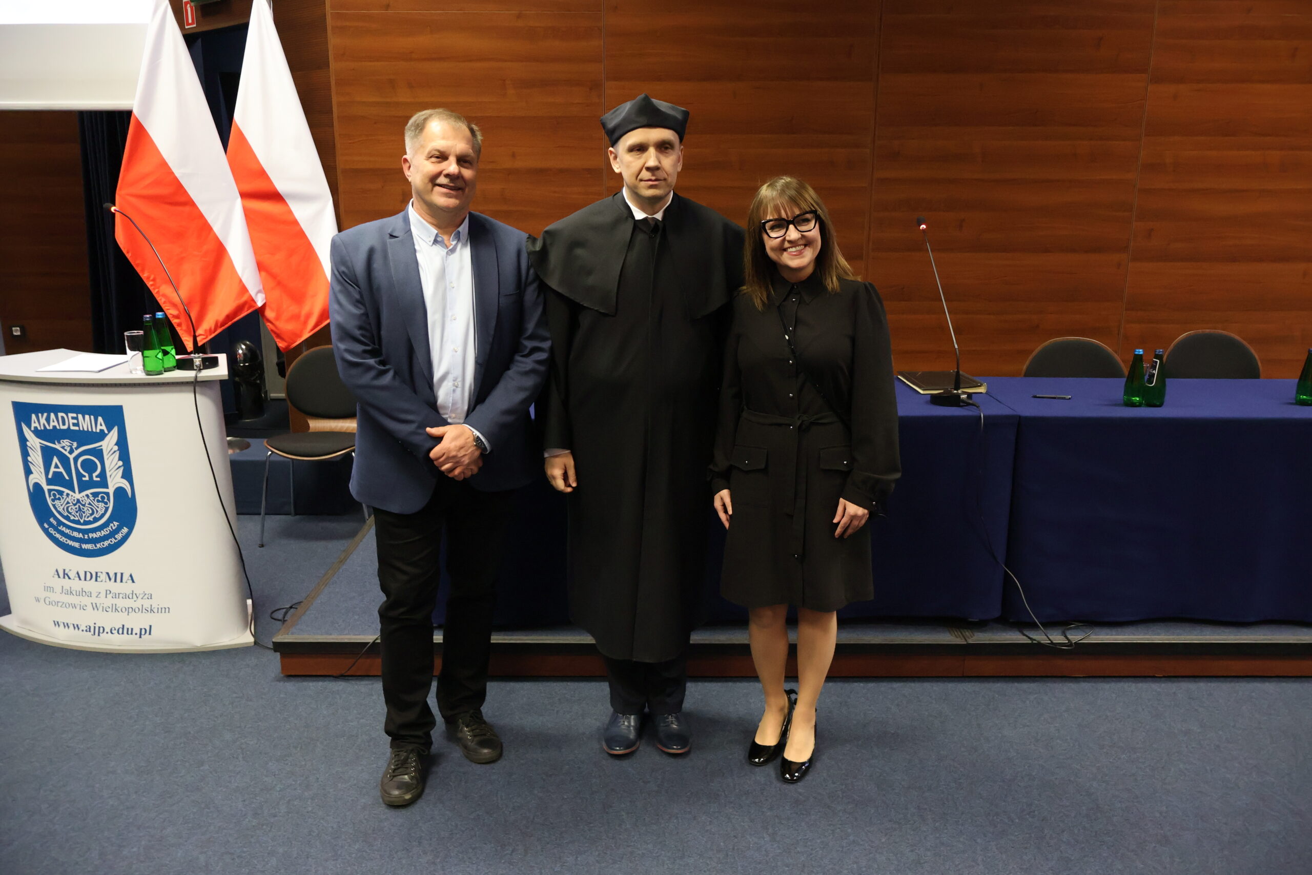 Stoją trzy osoby, dwóch mężczyzn i kobieta