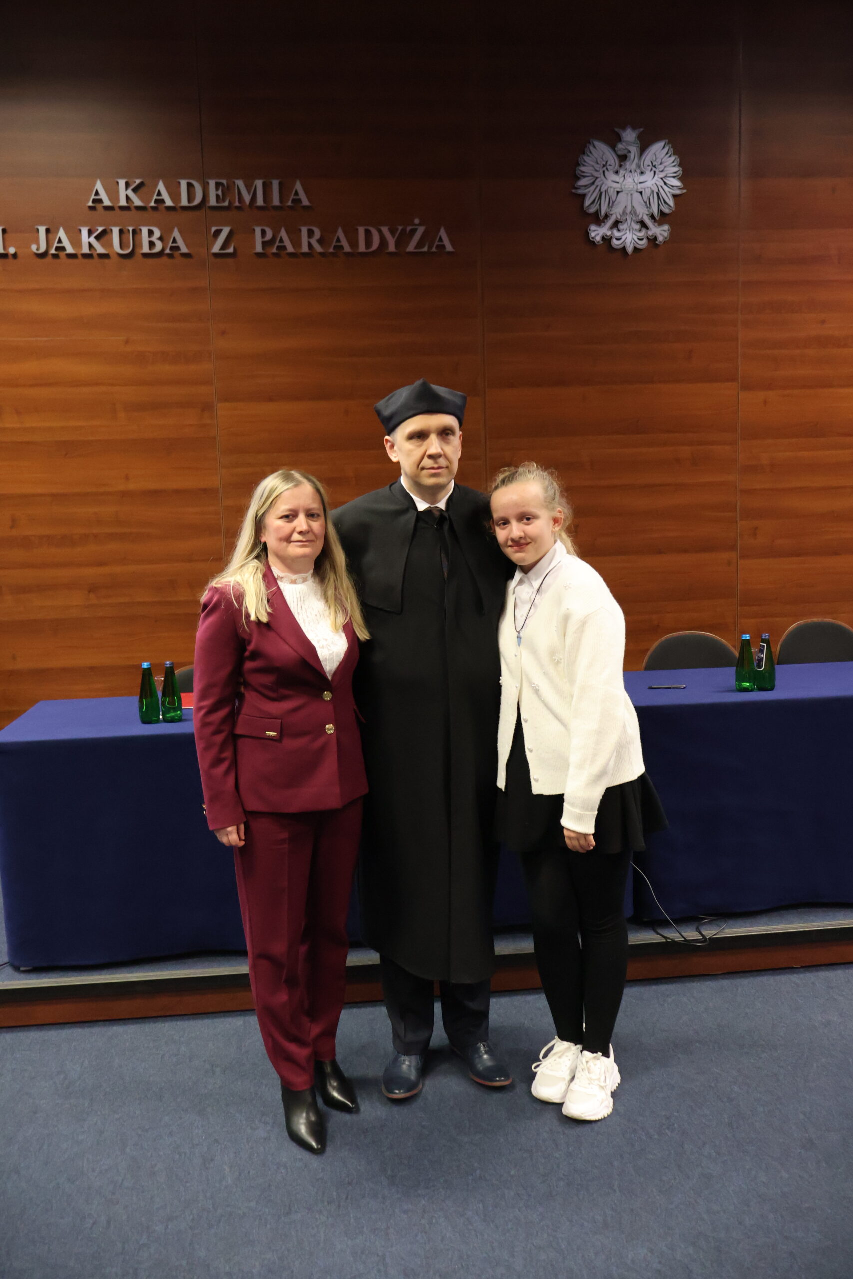 Na środku stoją 3 osoby: dr inż. Piotr Puzio z Rodziną