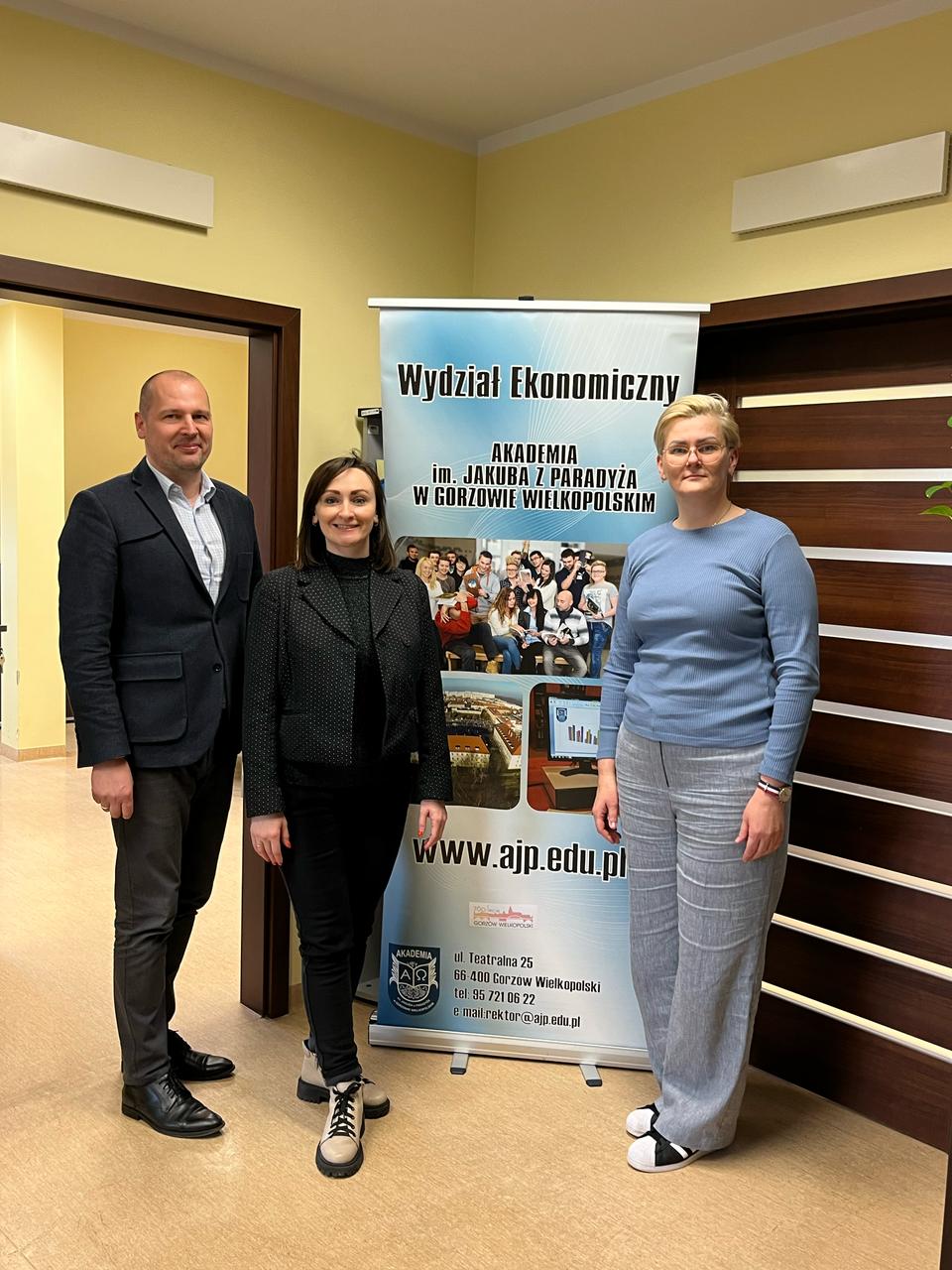 Prof. Piatnychuk z władzami Wydziału Ekonomicznego Panią Dziekan i Prodziekanem na tle baneru wydziałowego