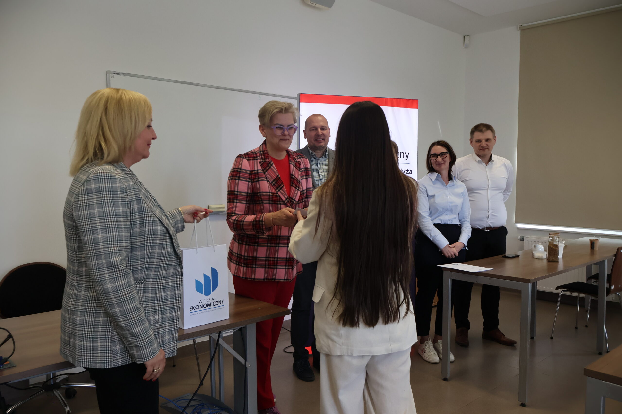 Uczestniczka konkursu odbiera prezent za uczestnictwo w konkursie.