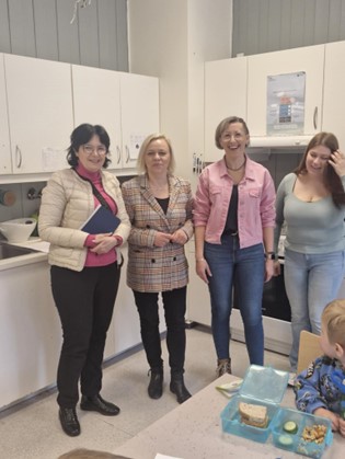 Obraz sali szkolnej, cztery stojące kobiety, ławka szkolna