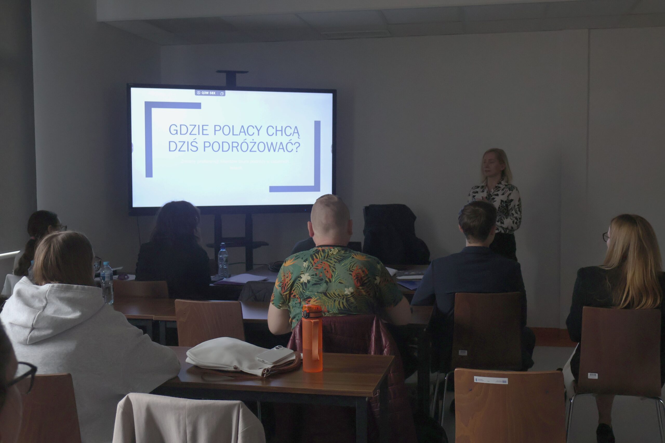 Prelegentka stoi podczas wygłaszania referatu w trakcie Seminarium, uczestnicy siedzą przed nią