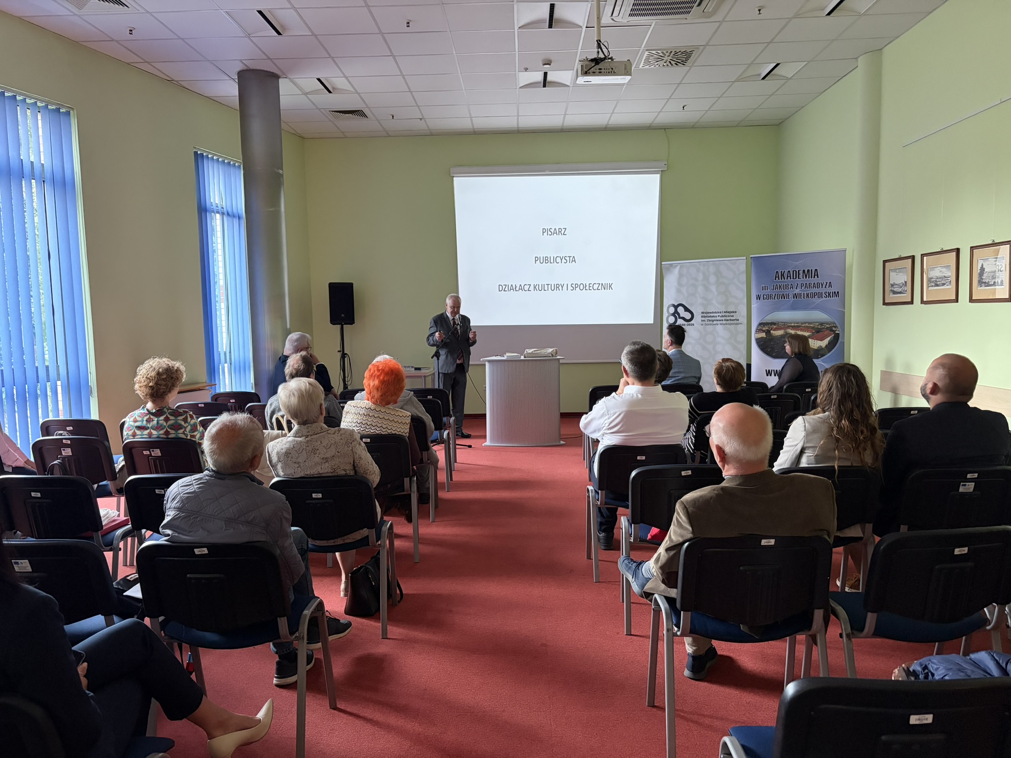 Prelegent przemawia i przedstawia swój referat - na slajdzie: pisarz, publicysta, działacz kultury i społecznik