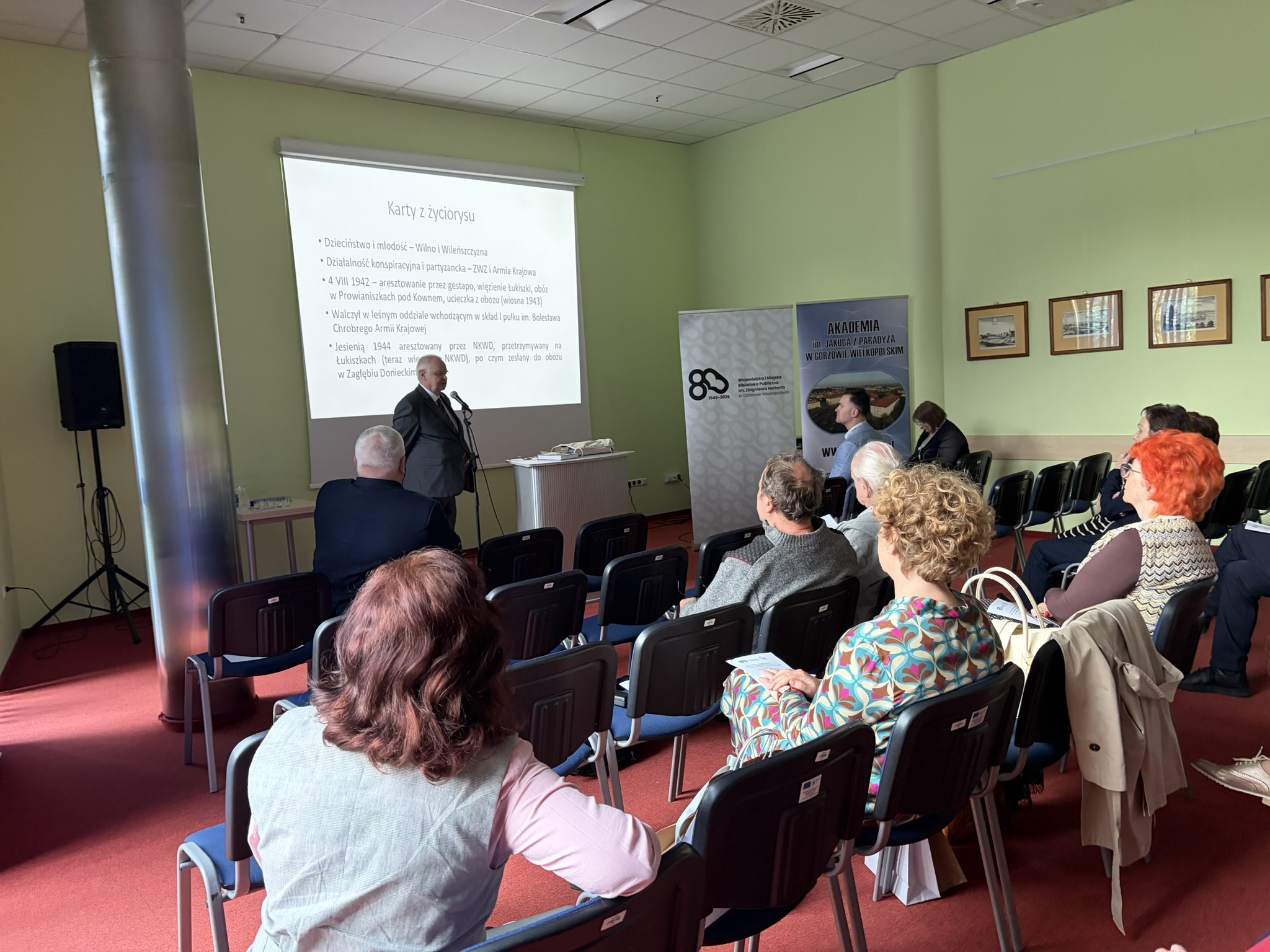 Prelegent przedstawia swój referat - Karty z życiorysu - slajd. Przed nim goście i słuchacze.