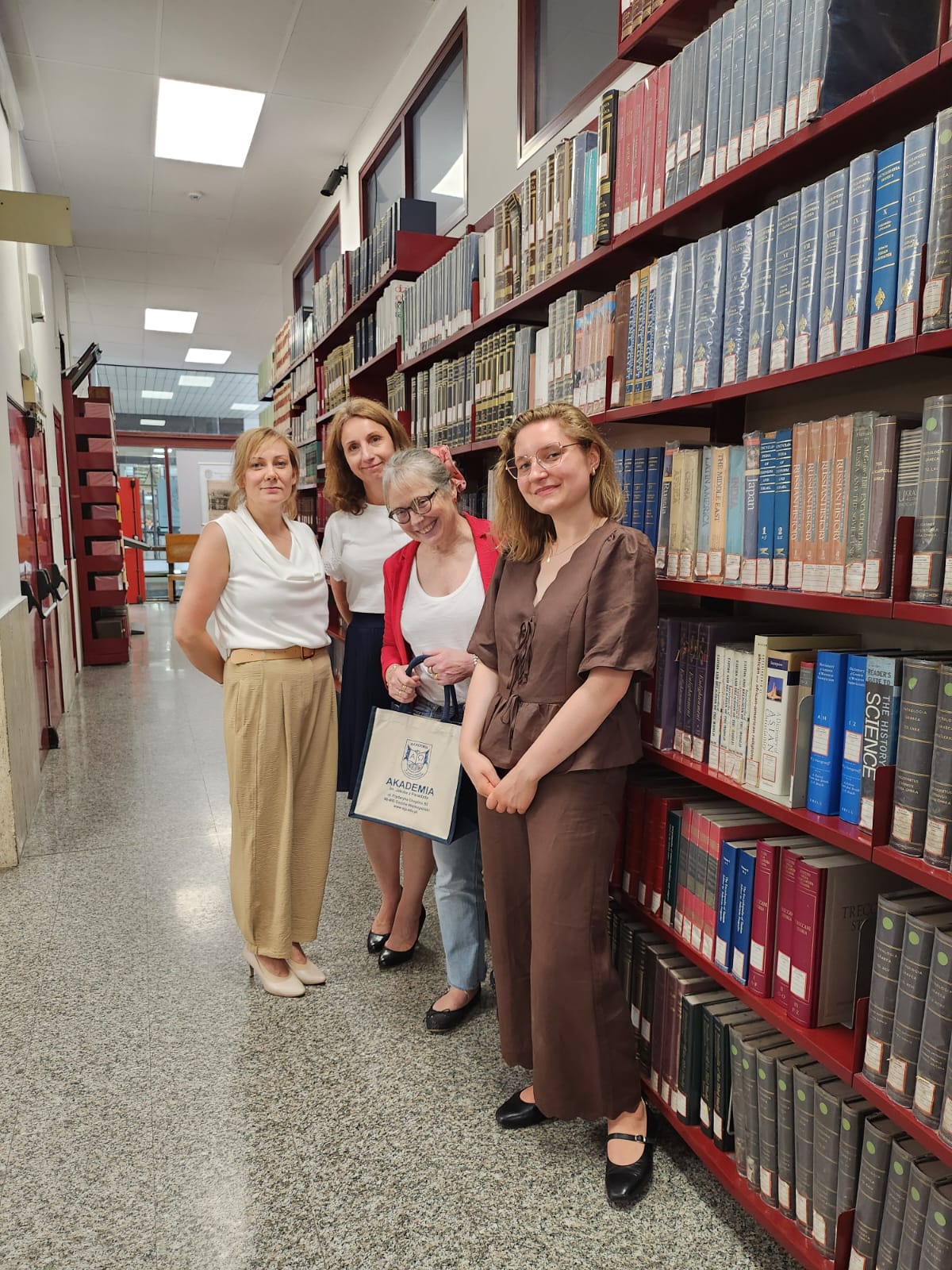 6. Trzy doktorantki z Dyrektor dr Danielą Fugaro na tle regałów bibliotecznych