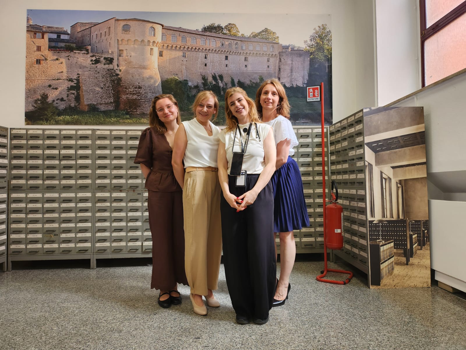 7. Pracownica biblioteki i trzy doktorantki na tle katalogów bibliotecznych