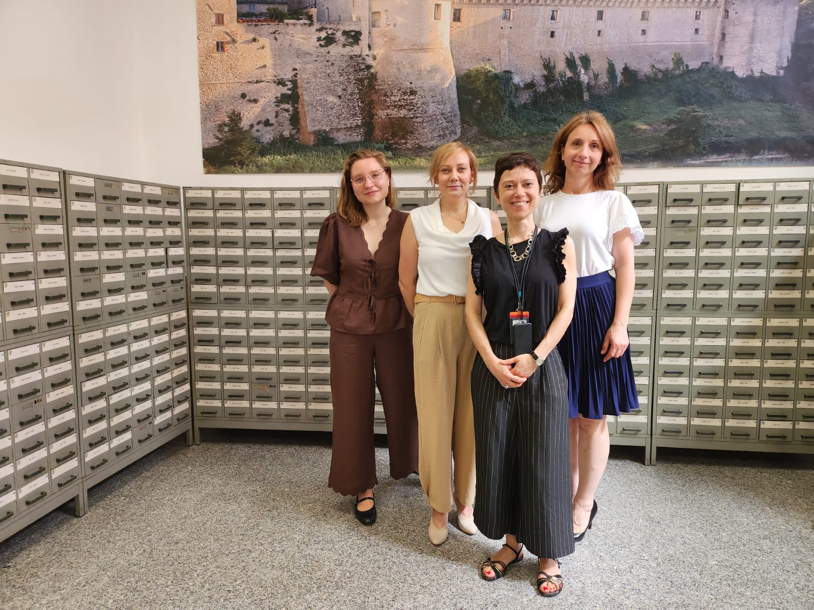 8. Pracownica biblioteki i trzy doktorantki na tle katalogów bibliotecznych